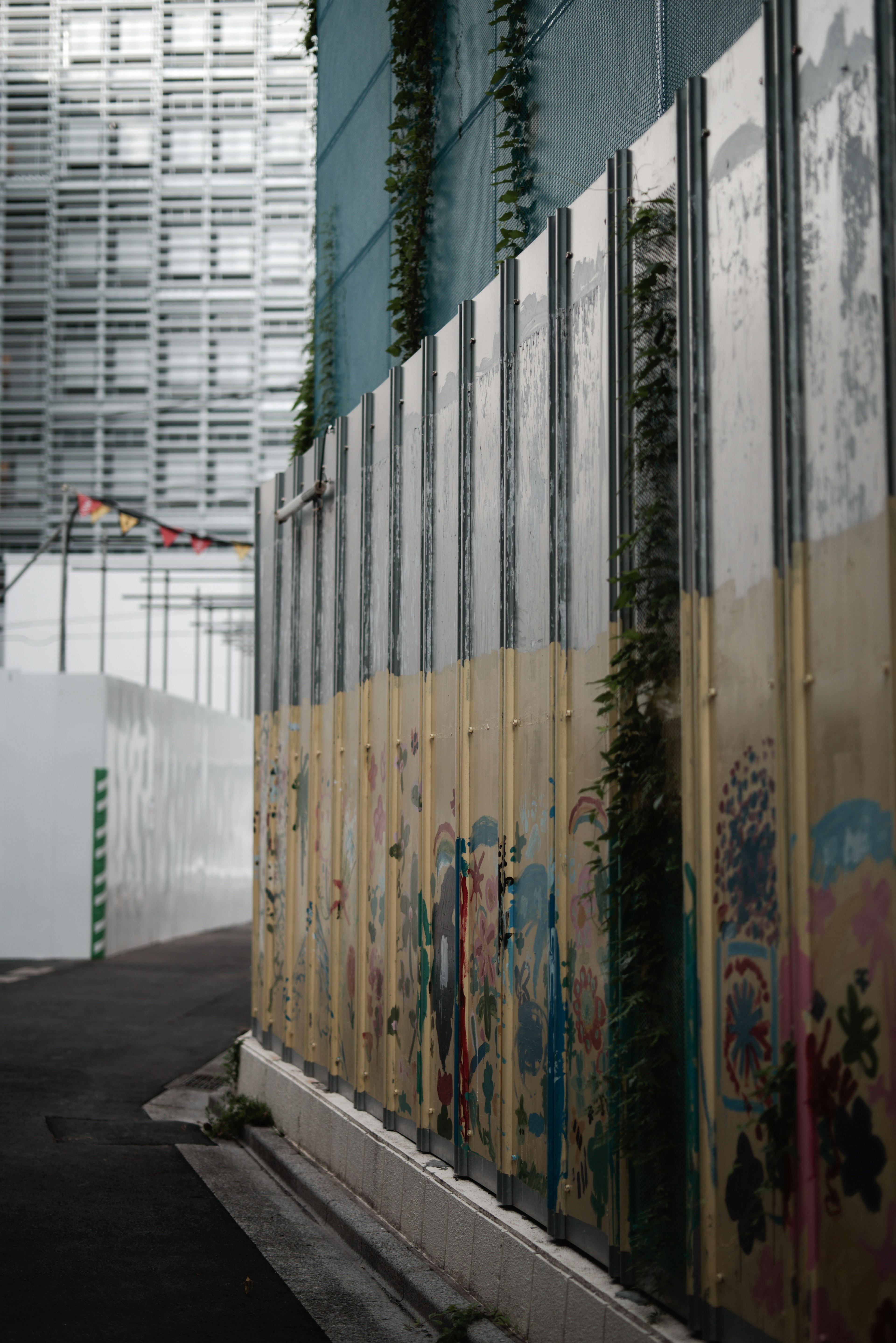 Buntes Graffiti an einer Baustellenwand mit verwobenen grünen Pflanzen