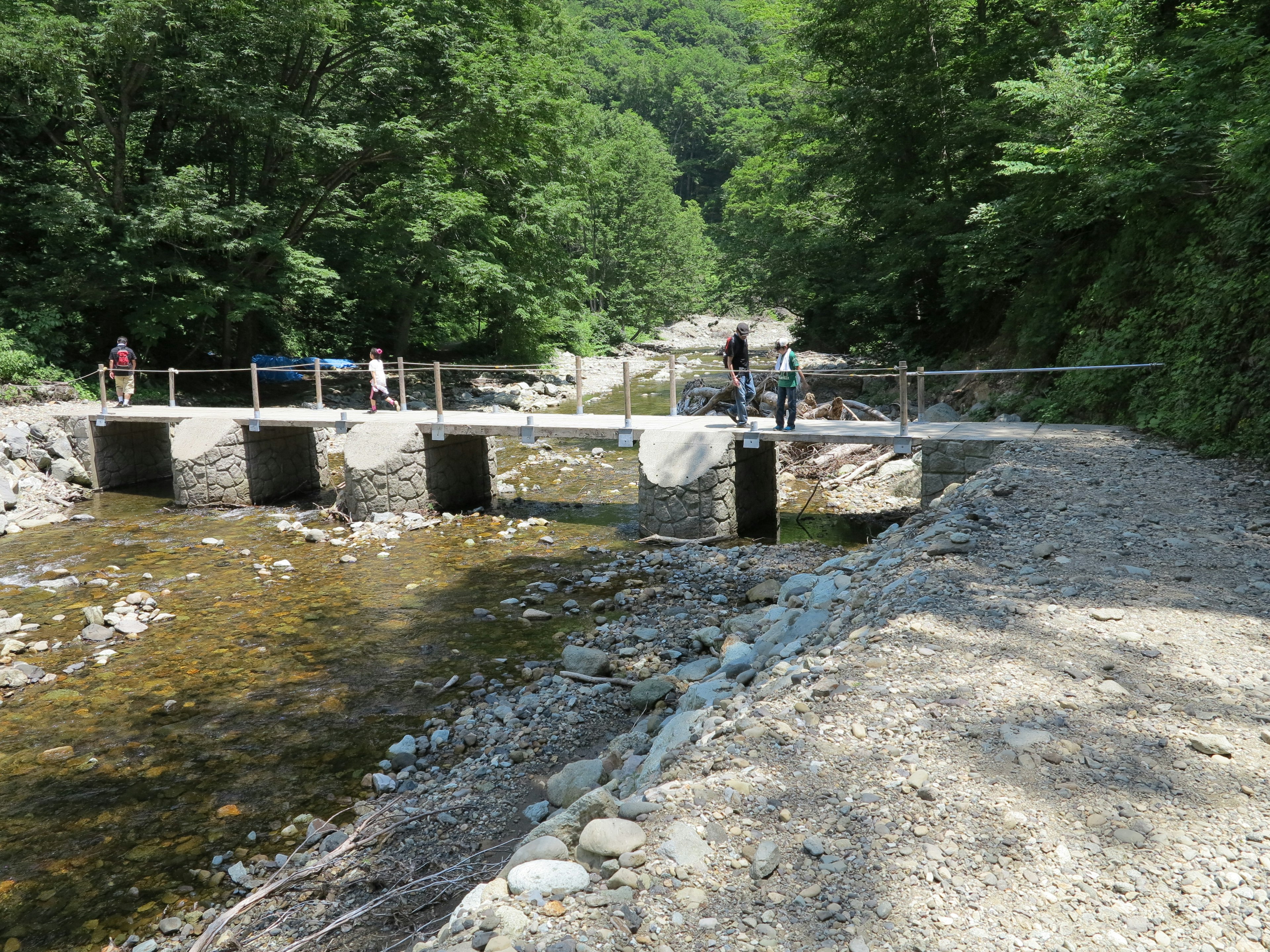 Ponte in pietra su un ruscello circondato da verde e persone