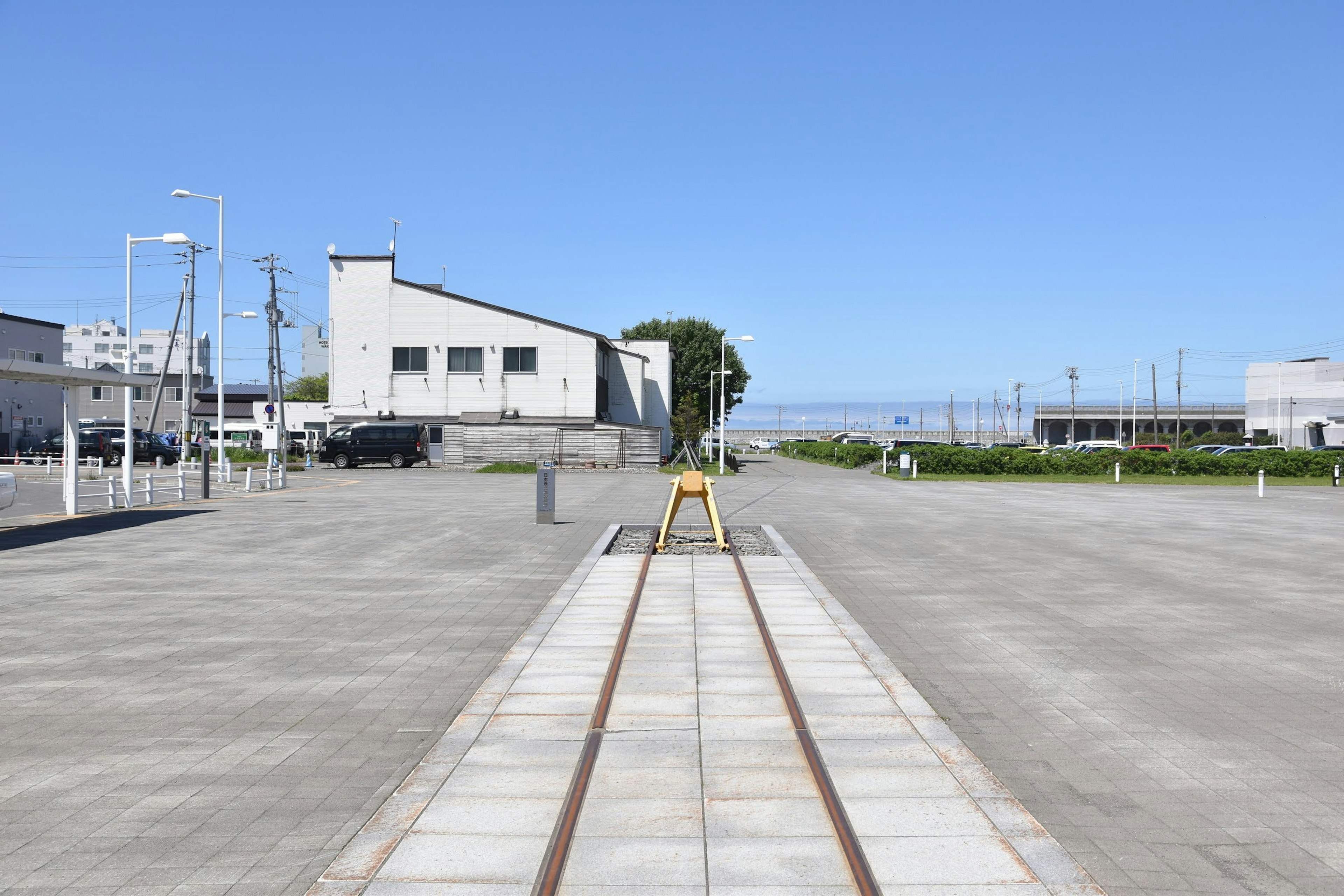 Railroad tracks leading into a clear blue sky with a concrete area