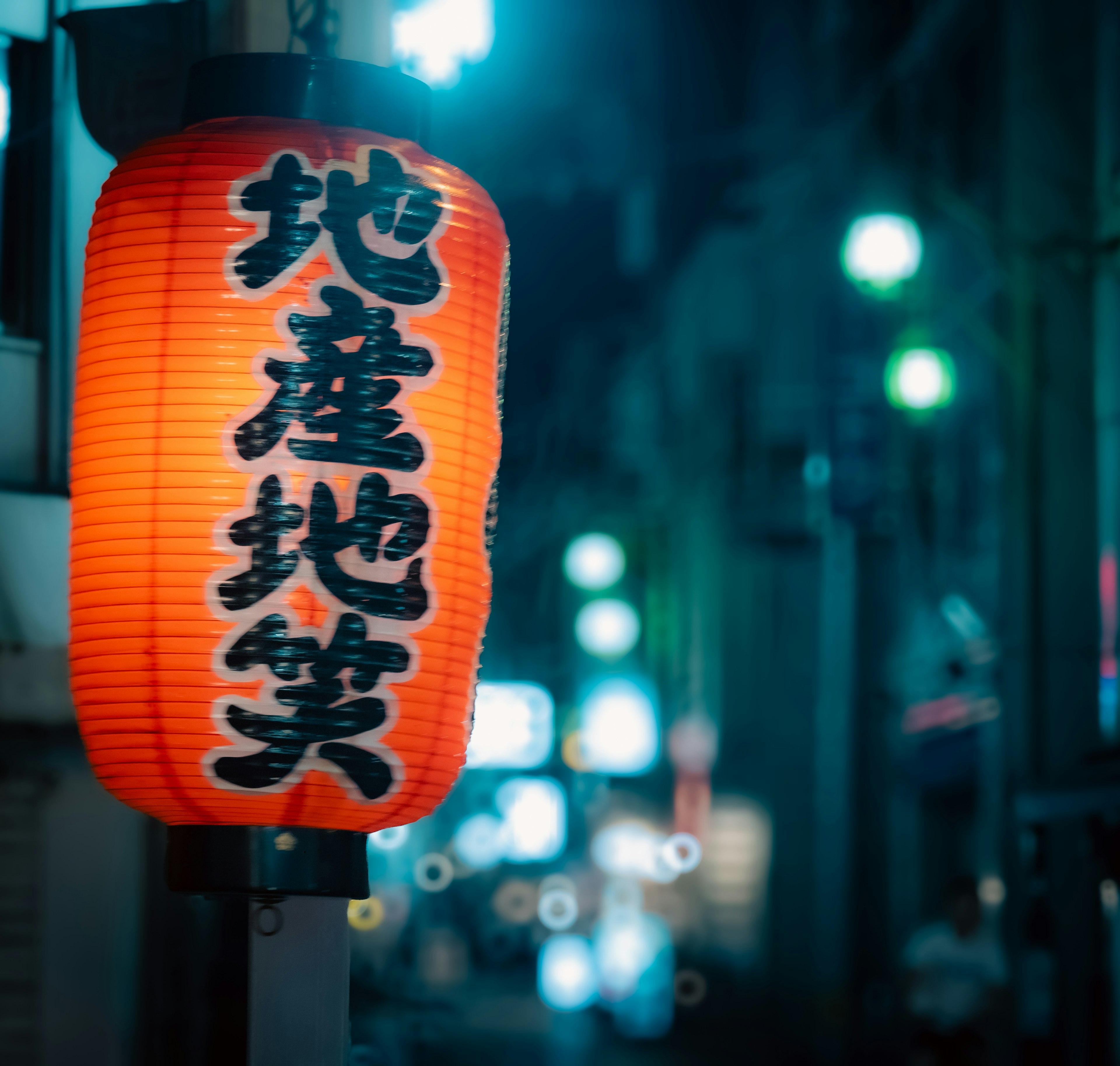 Red lantern glowing softly in the night with Japanese text