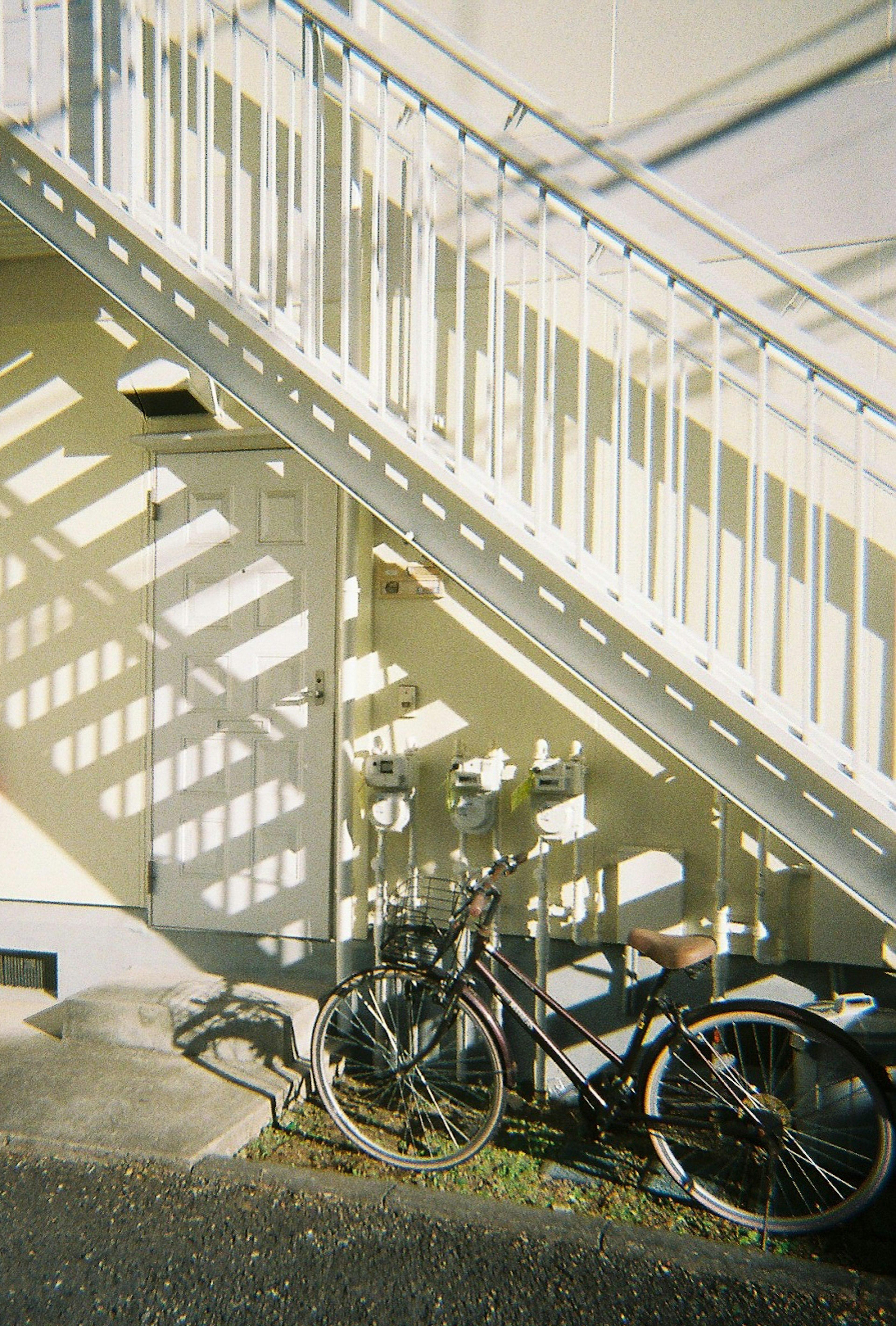 Bicycle parked under a staircase with striking shadow patterns