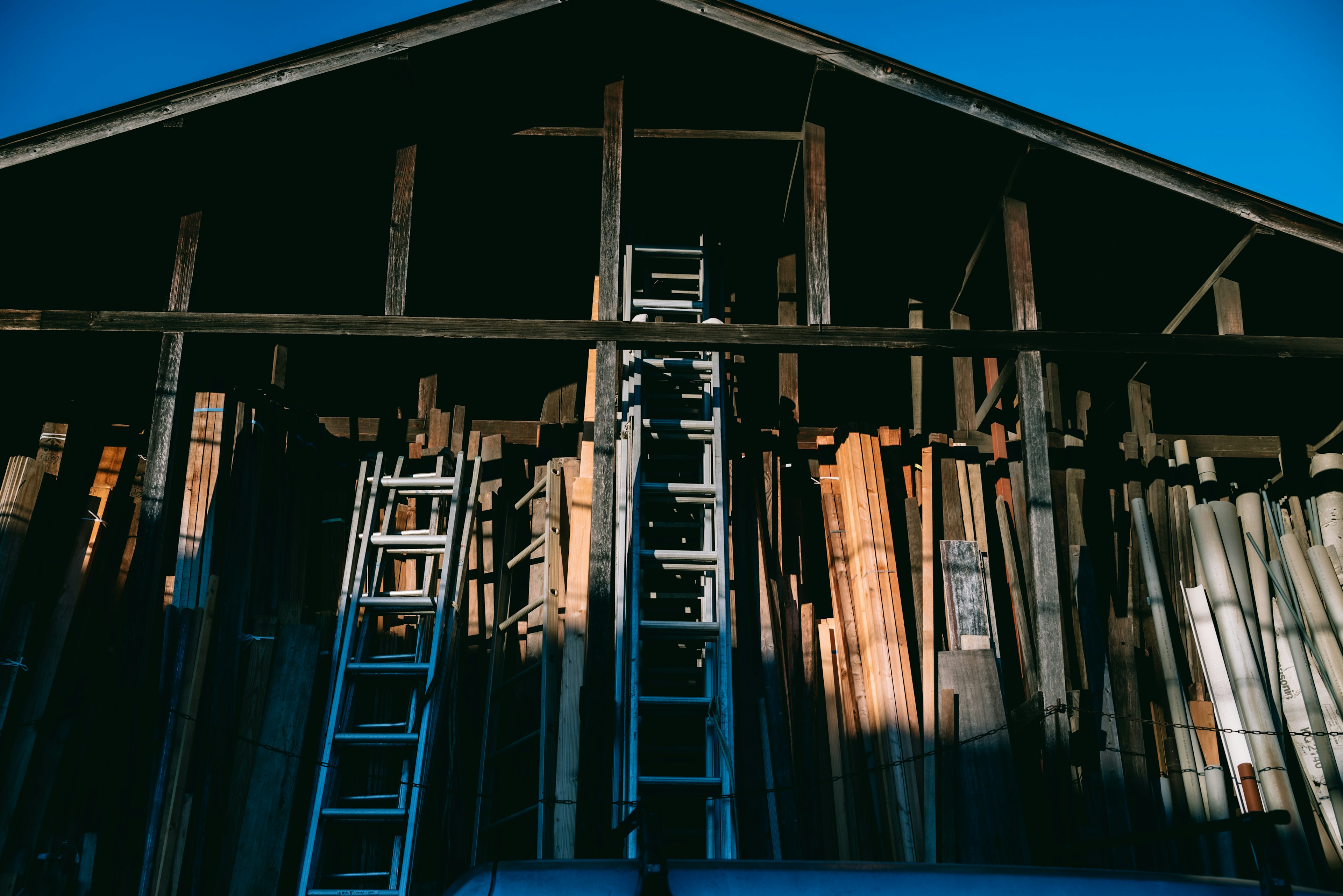 Exterior of a warehouse with stacked lumber and ladders