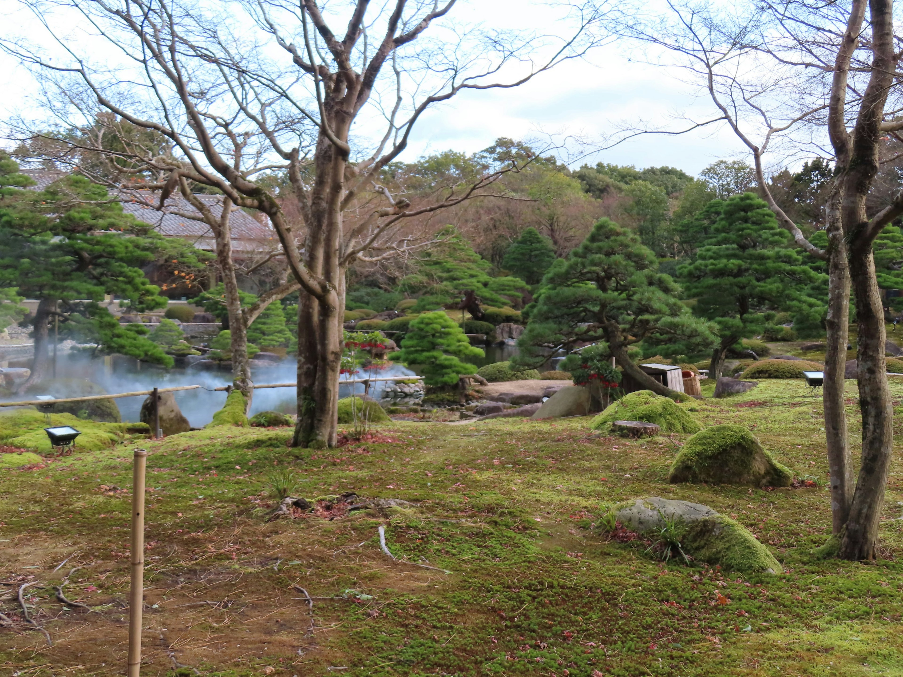 Ruhige japanische Gartenlandschaft mit Bäumen und Steinen in der Nähe einer ruhigen Wasseroberfläche