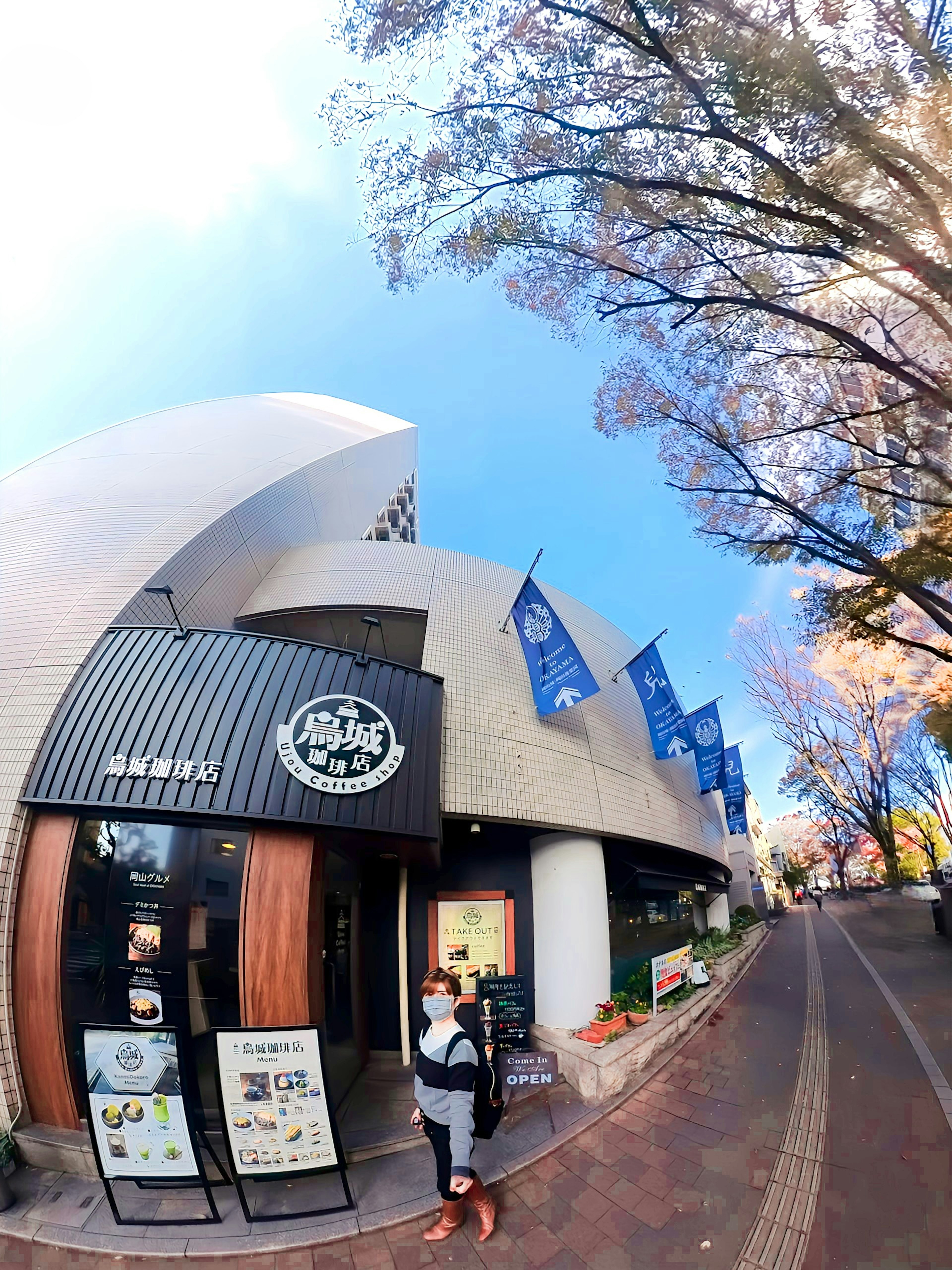 Stylish café exterior under a blue sky with trees lining the street