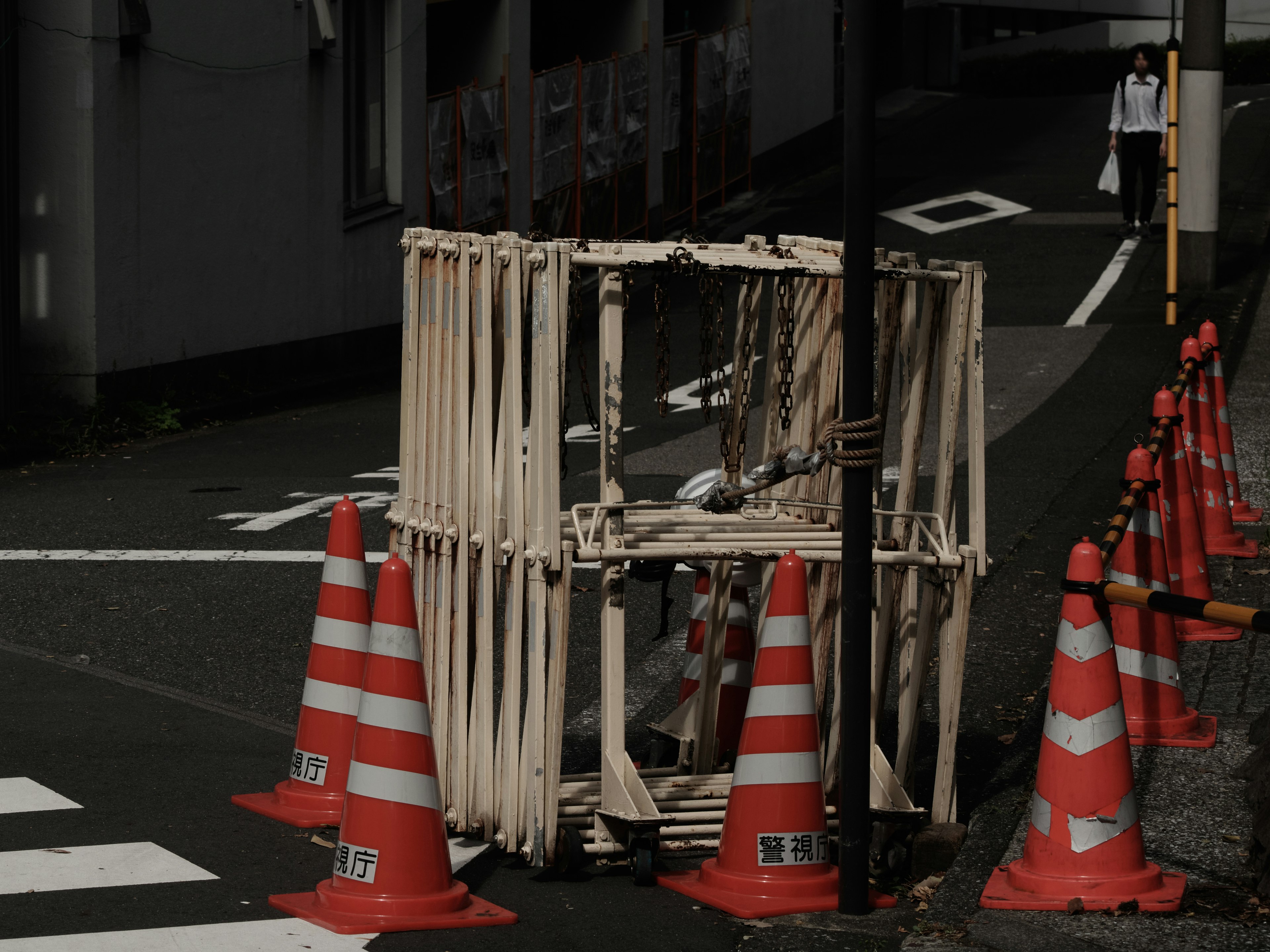 赤いコーンに囲まれた木製の作業用囲いがある街角の風景