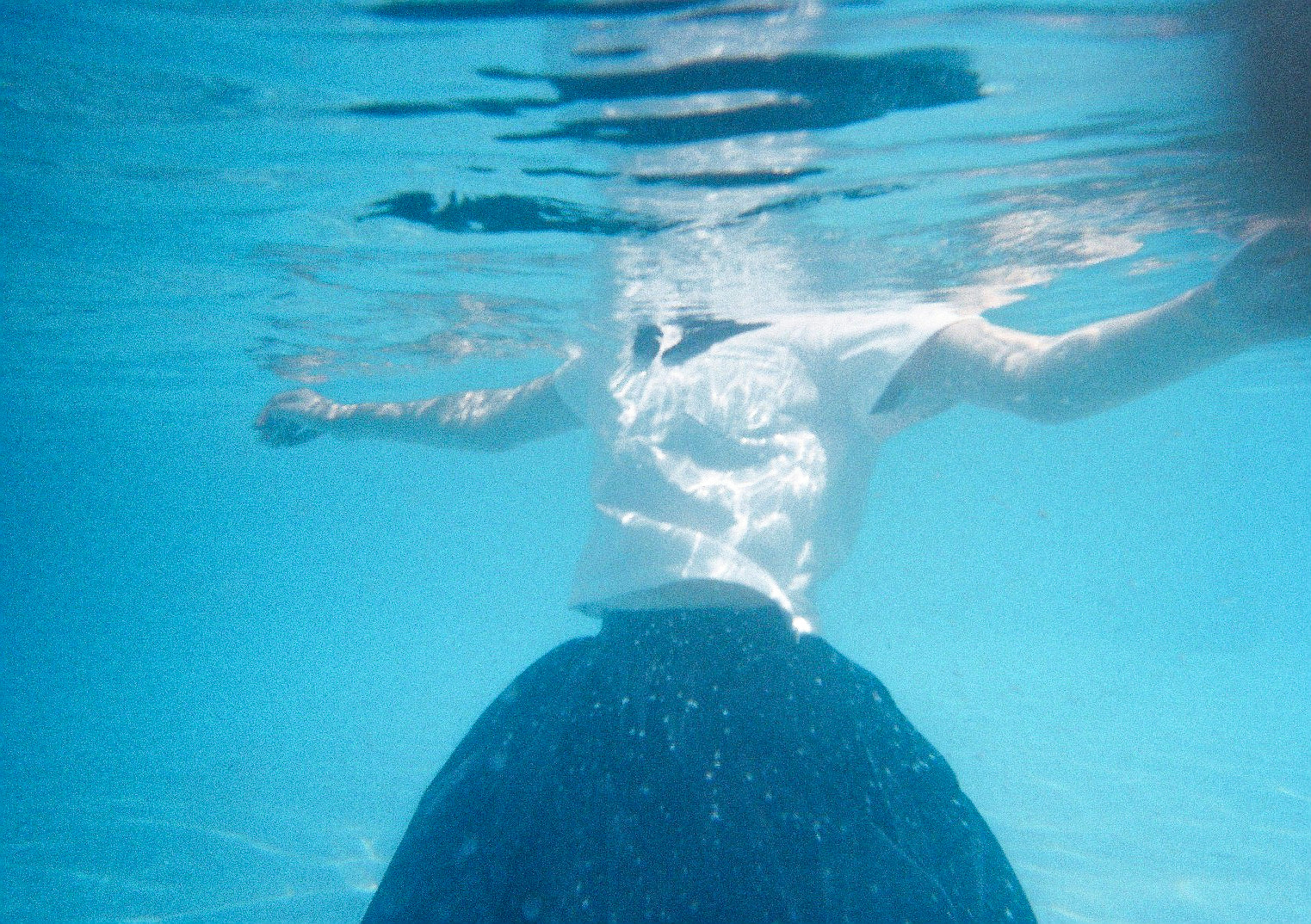 Personne flottant sous l'eau avec une jupe bleue et un haut blanc