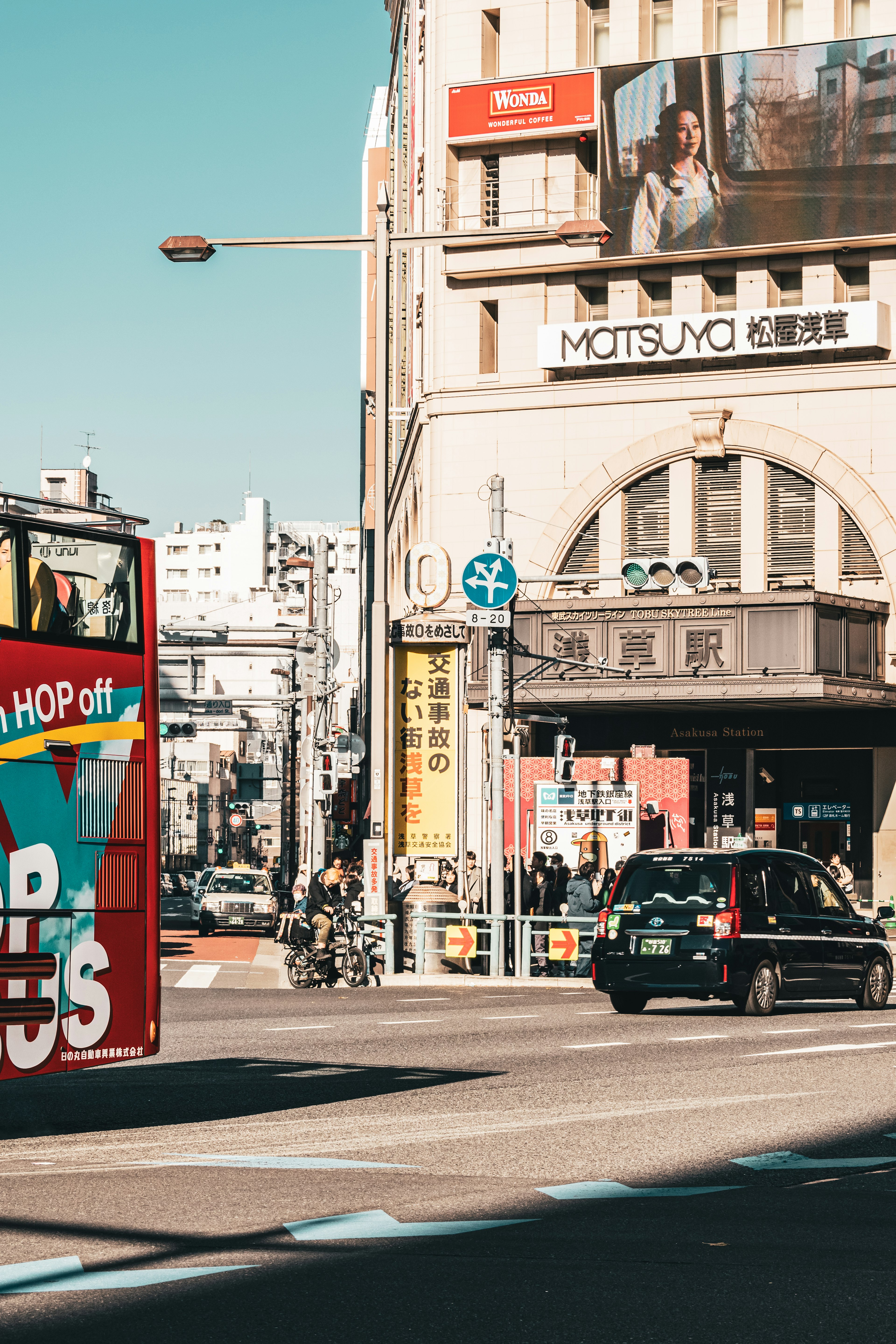 Belebte Straßenecke mit einem roten Sightseeing-Bus und einem Taxi in Bewegung