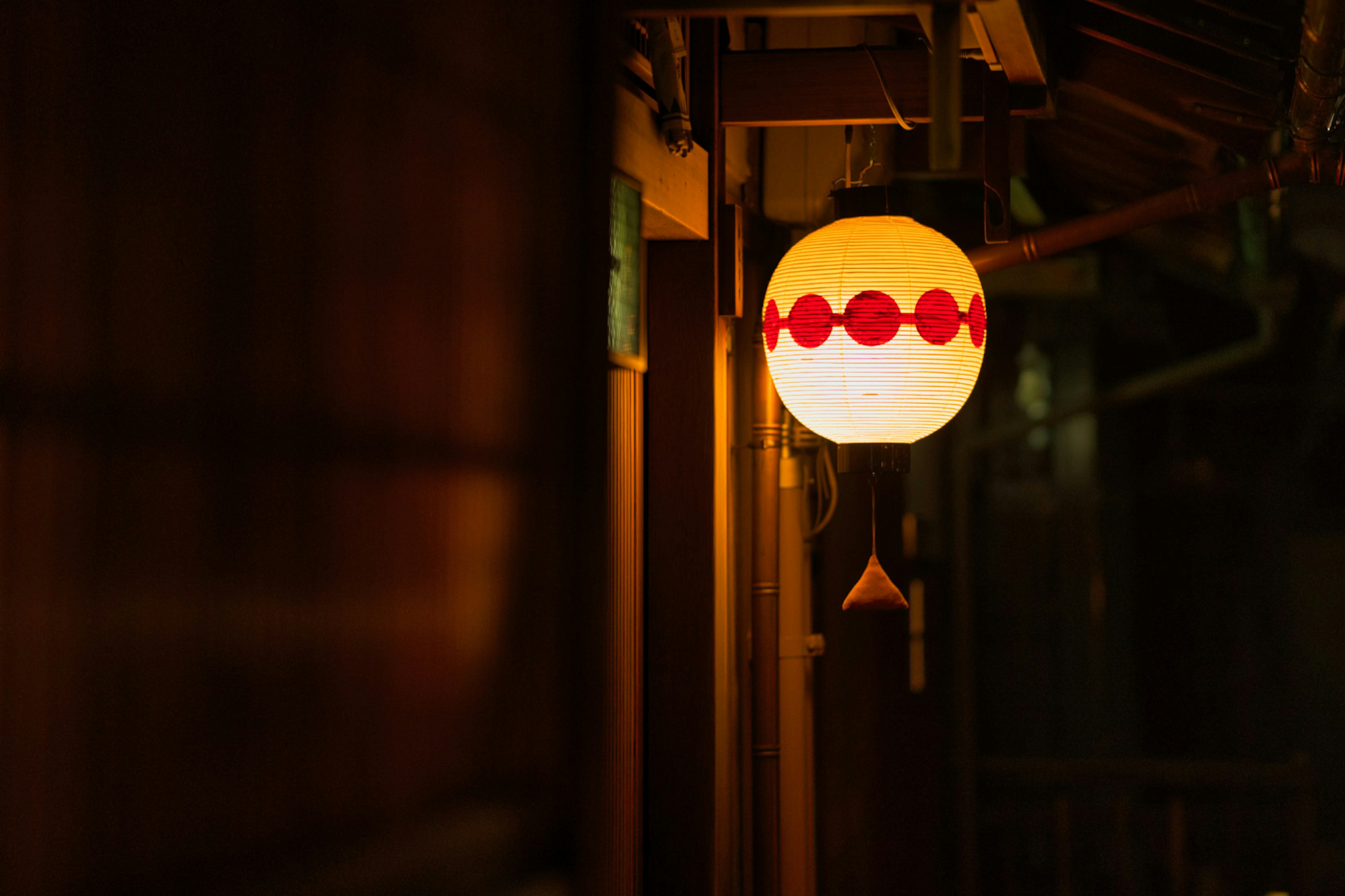 Linterna japonesa con puntos rojos iluminada en un entorno oscuro