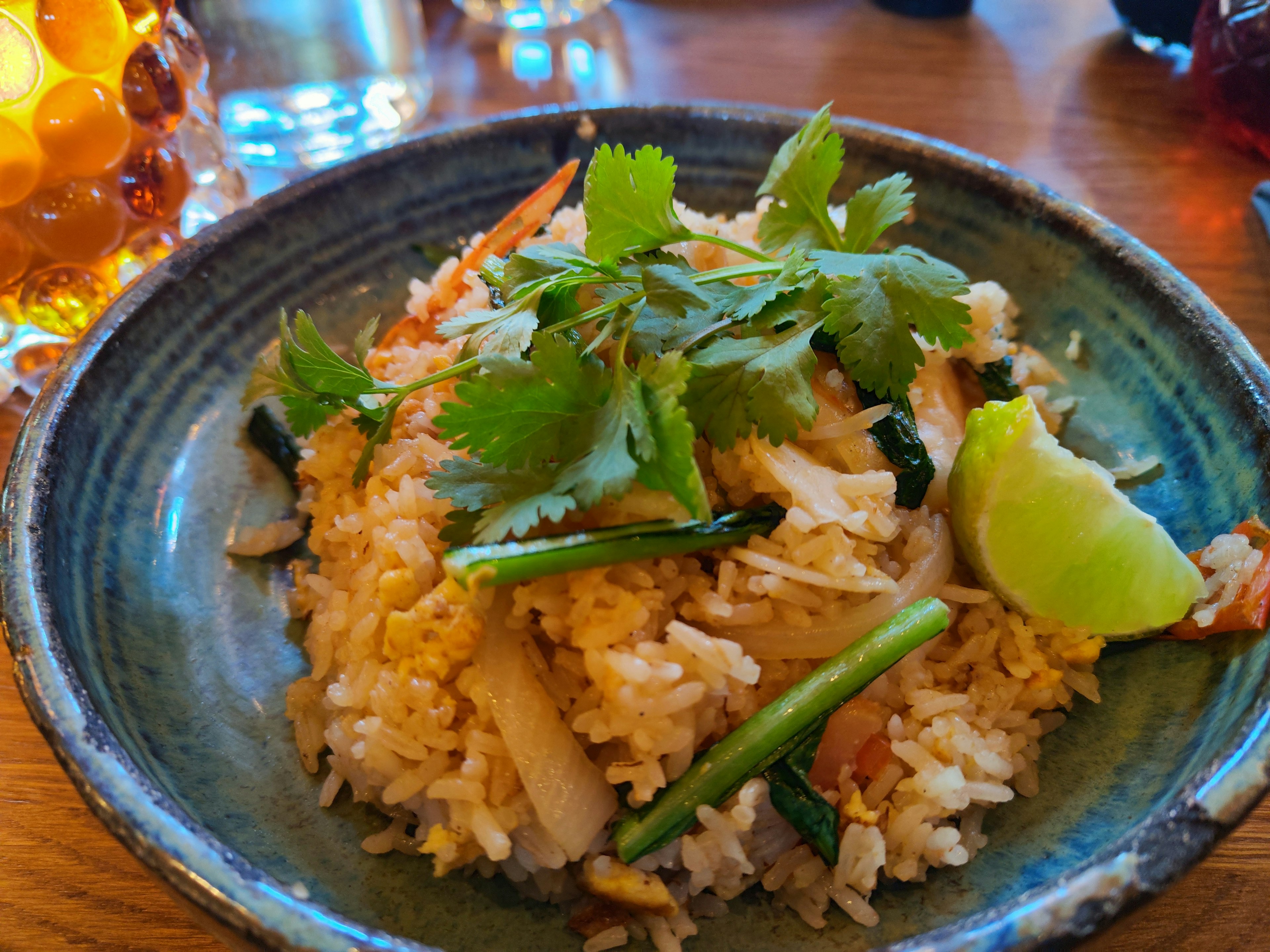 Plate of fried rice topped with herbs and lime