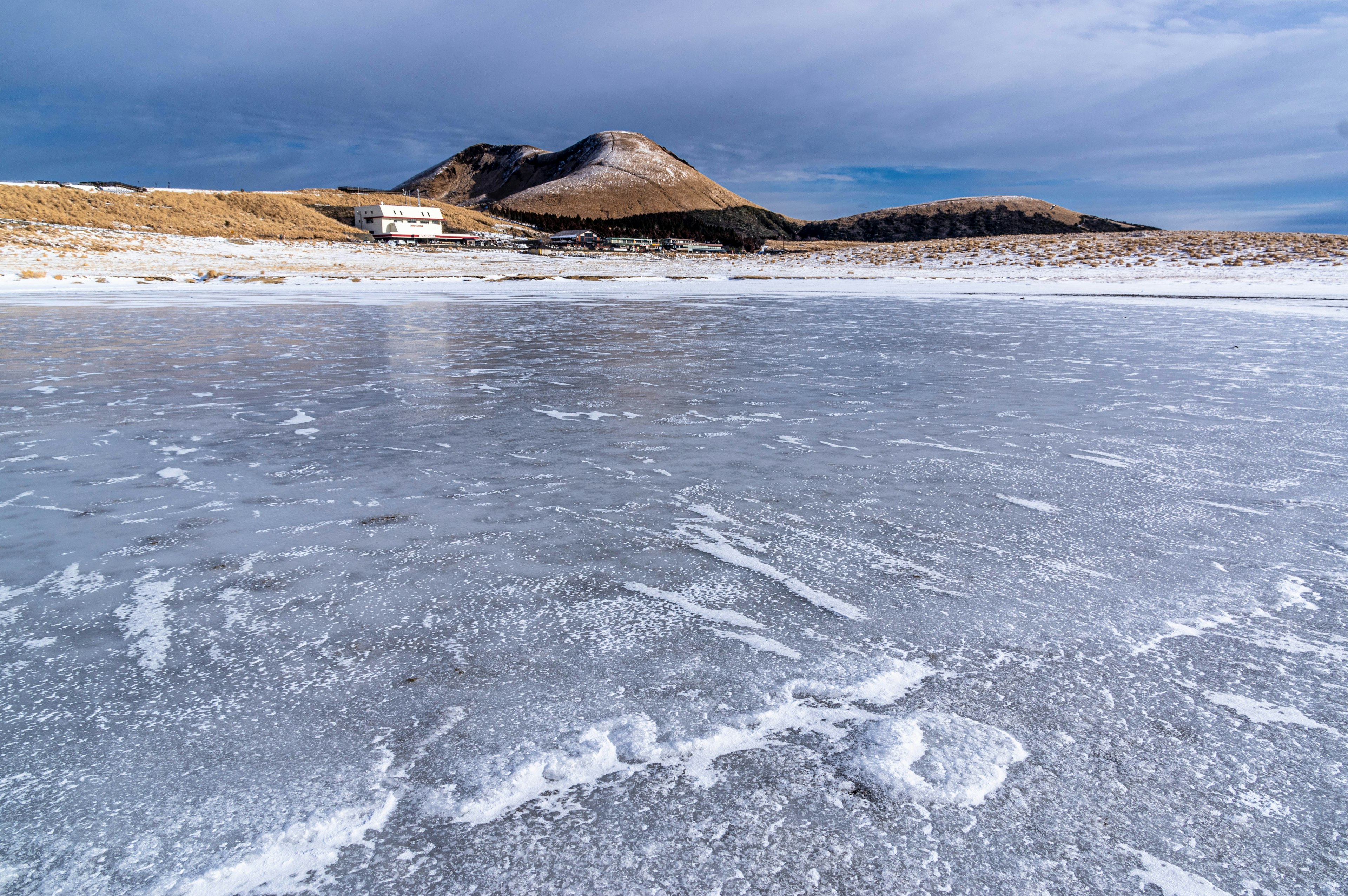 Gefrorener See mit Bergkulisse unter einem bewölkten Himmel