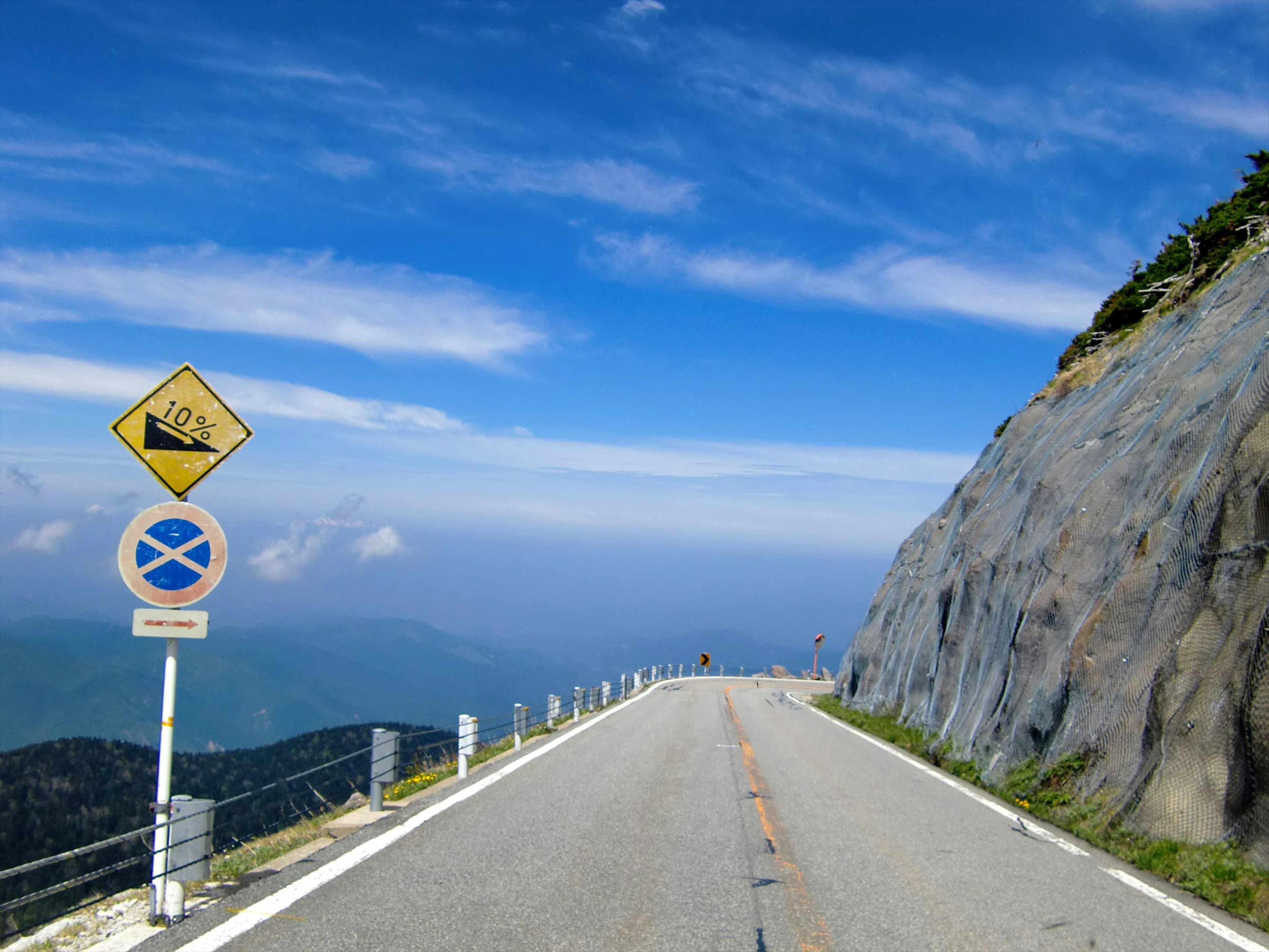 Route de montagne sous un ciel bleu avec panneau d'avertissement