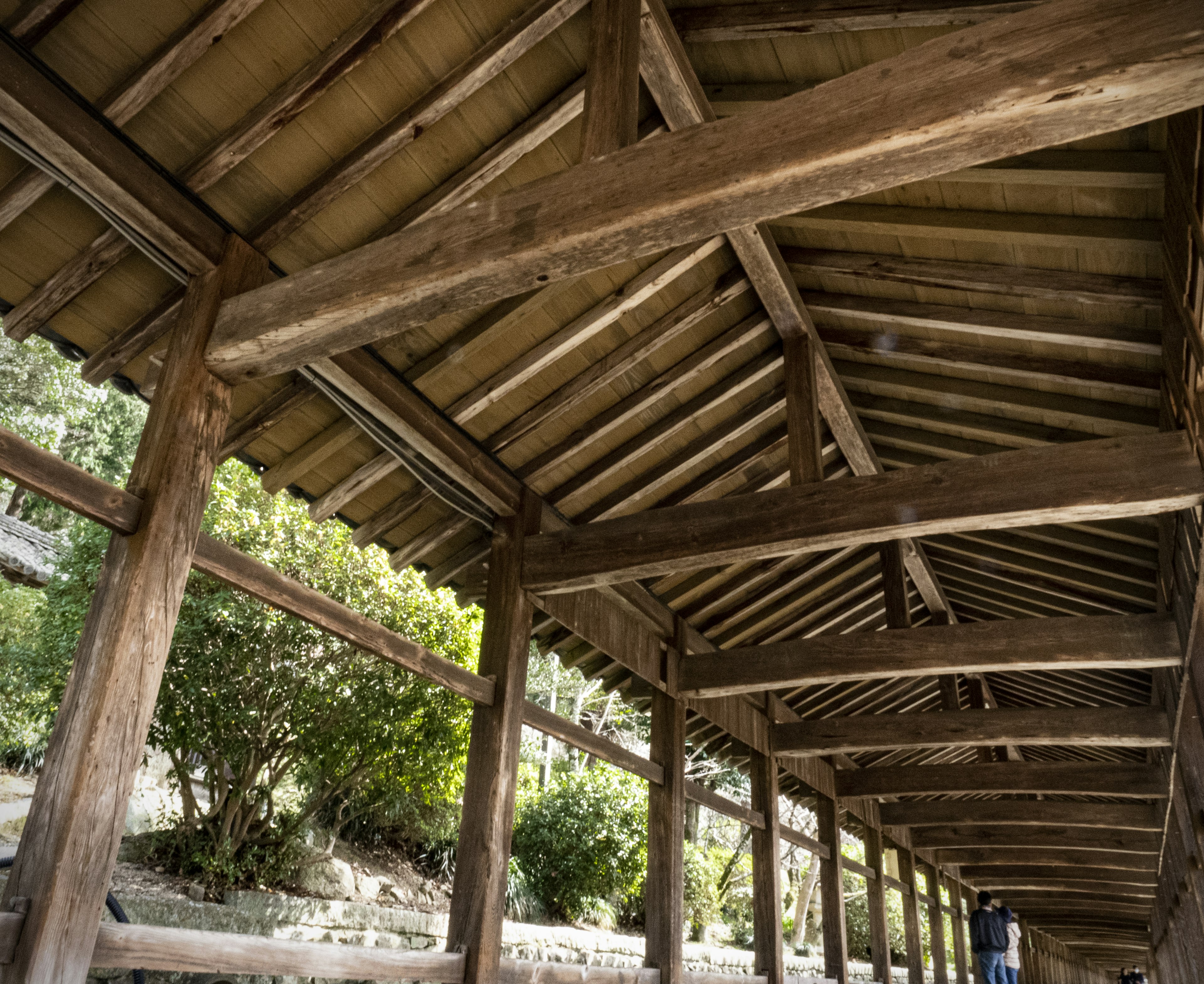 Vista interior de un paseo de madera con un techo inclinado y vigas de soporte