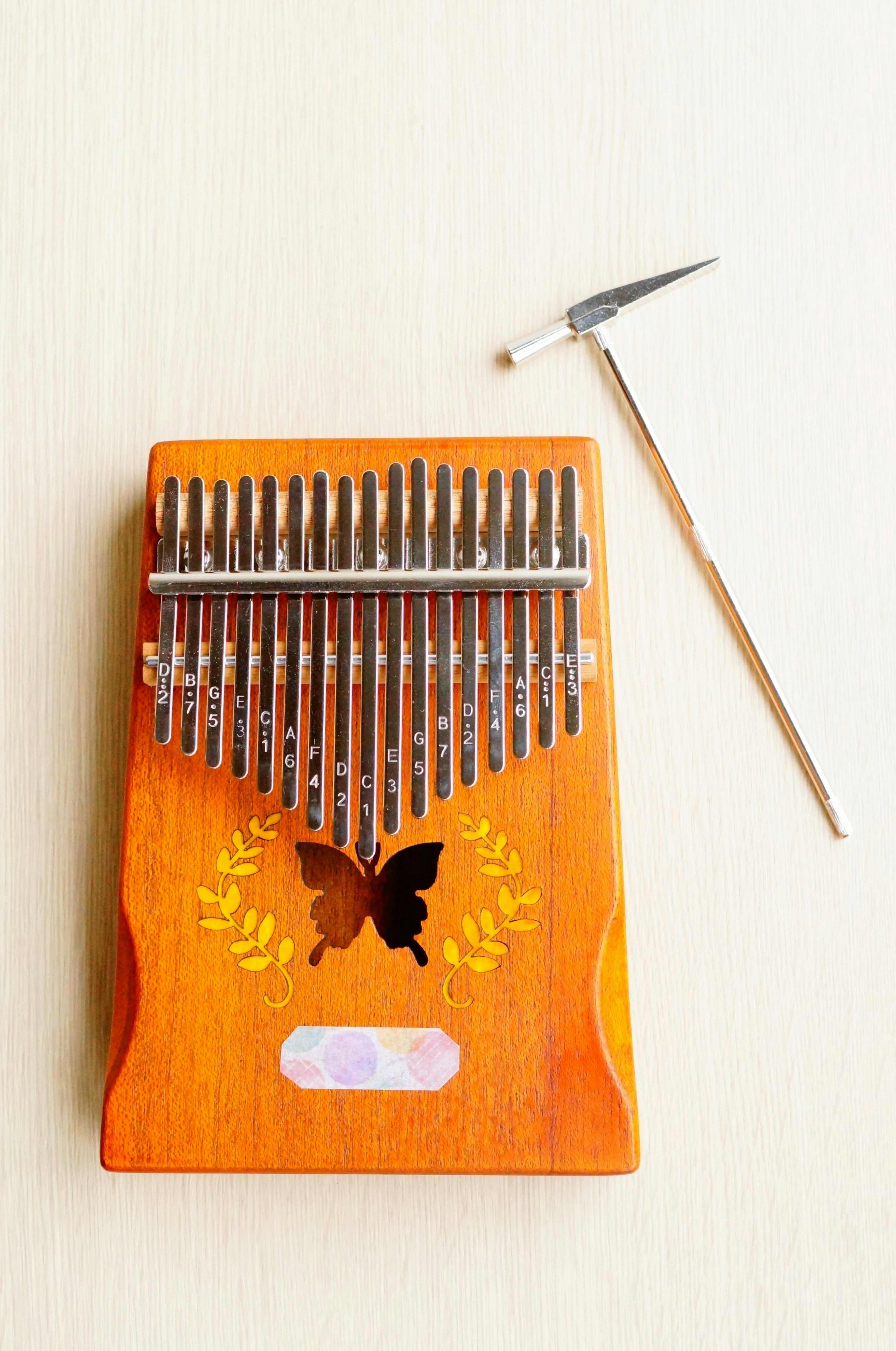 Kalimba de madera con lengüetas de metal y un mazo al lado