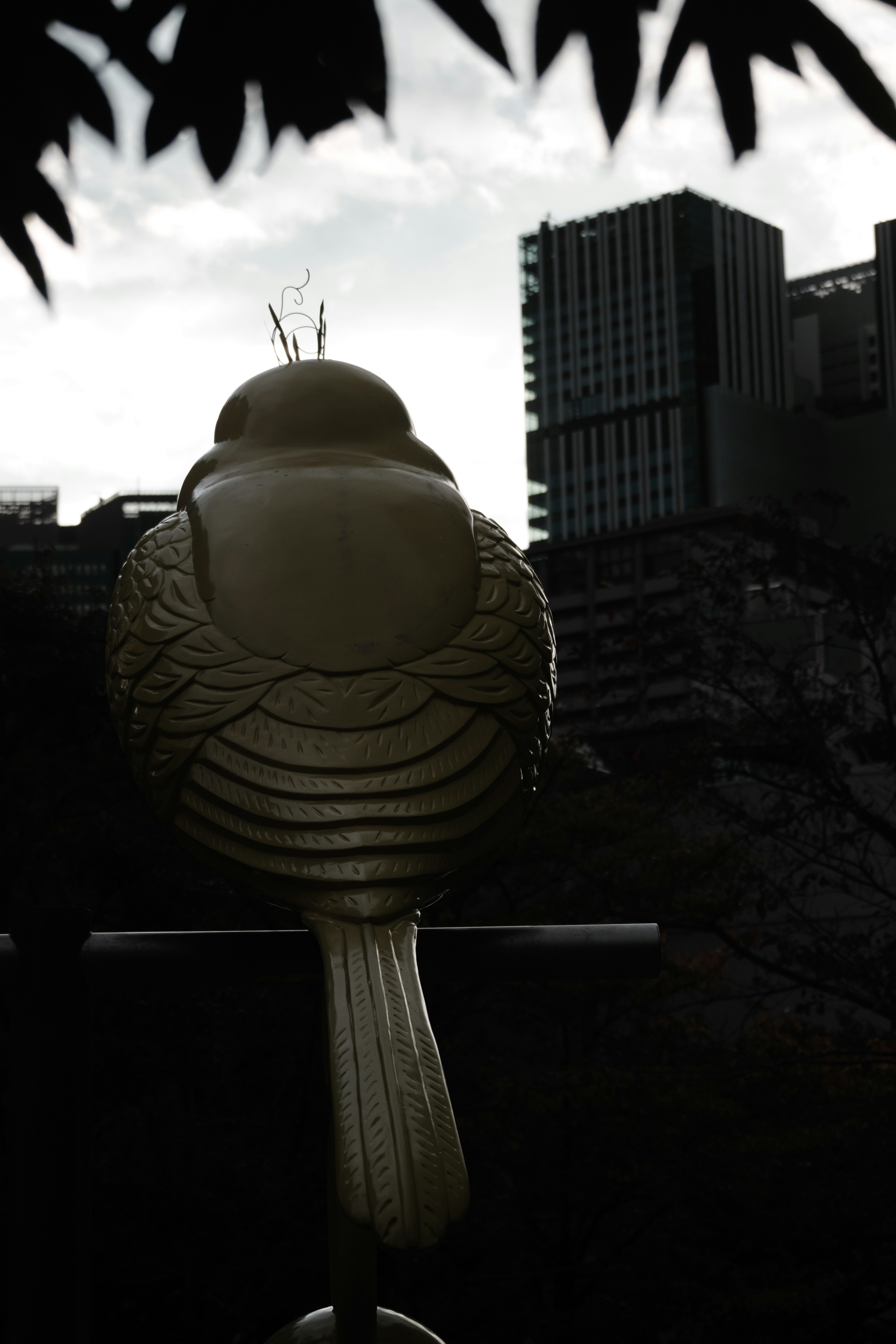 Silhouette of a bird sculpture with modern buildings in the background