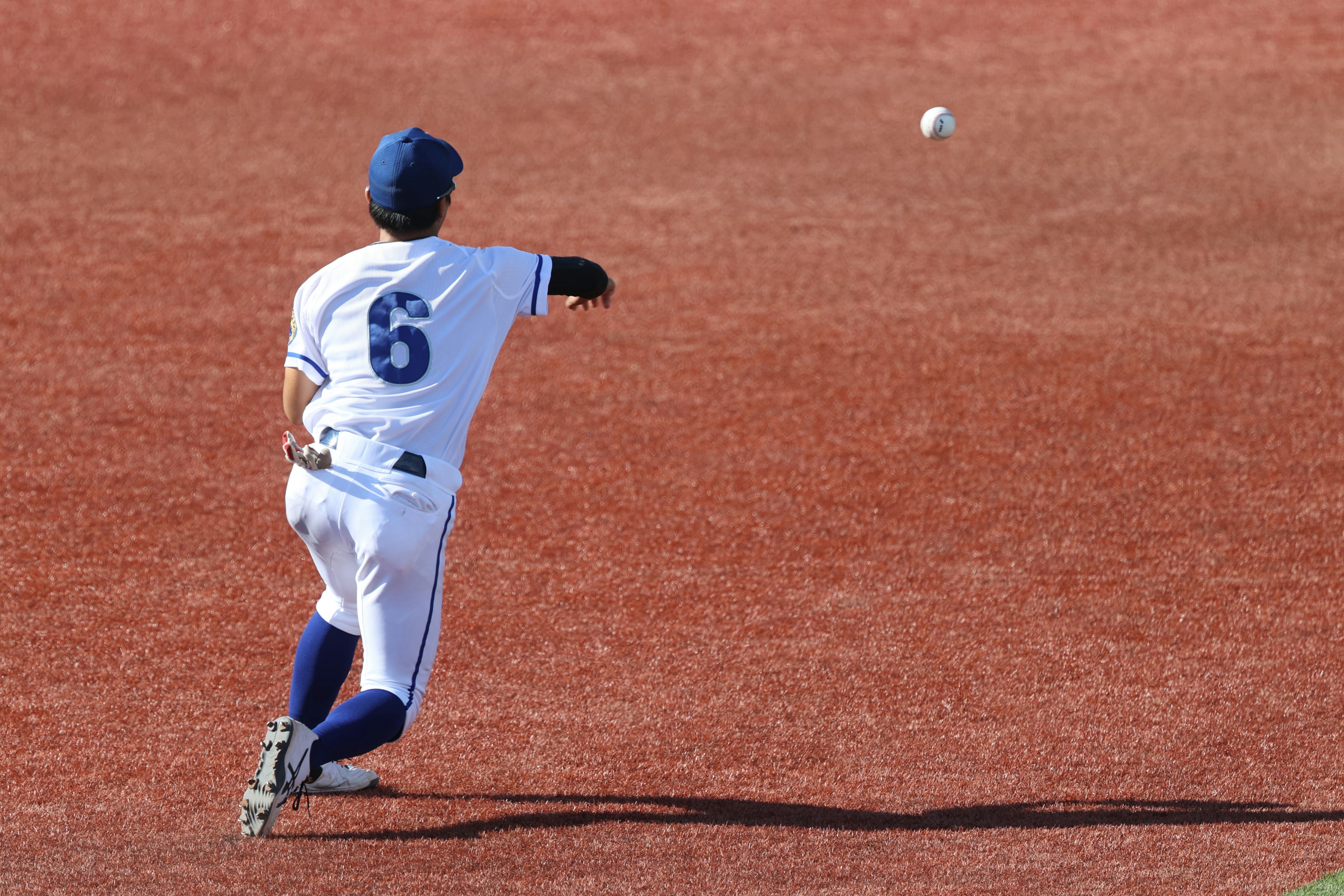 Un giocatore di baseball che lancia una palla su un campo rosso