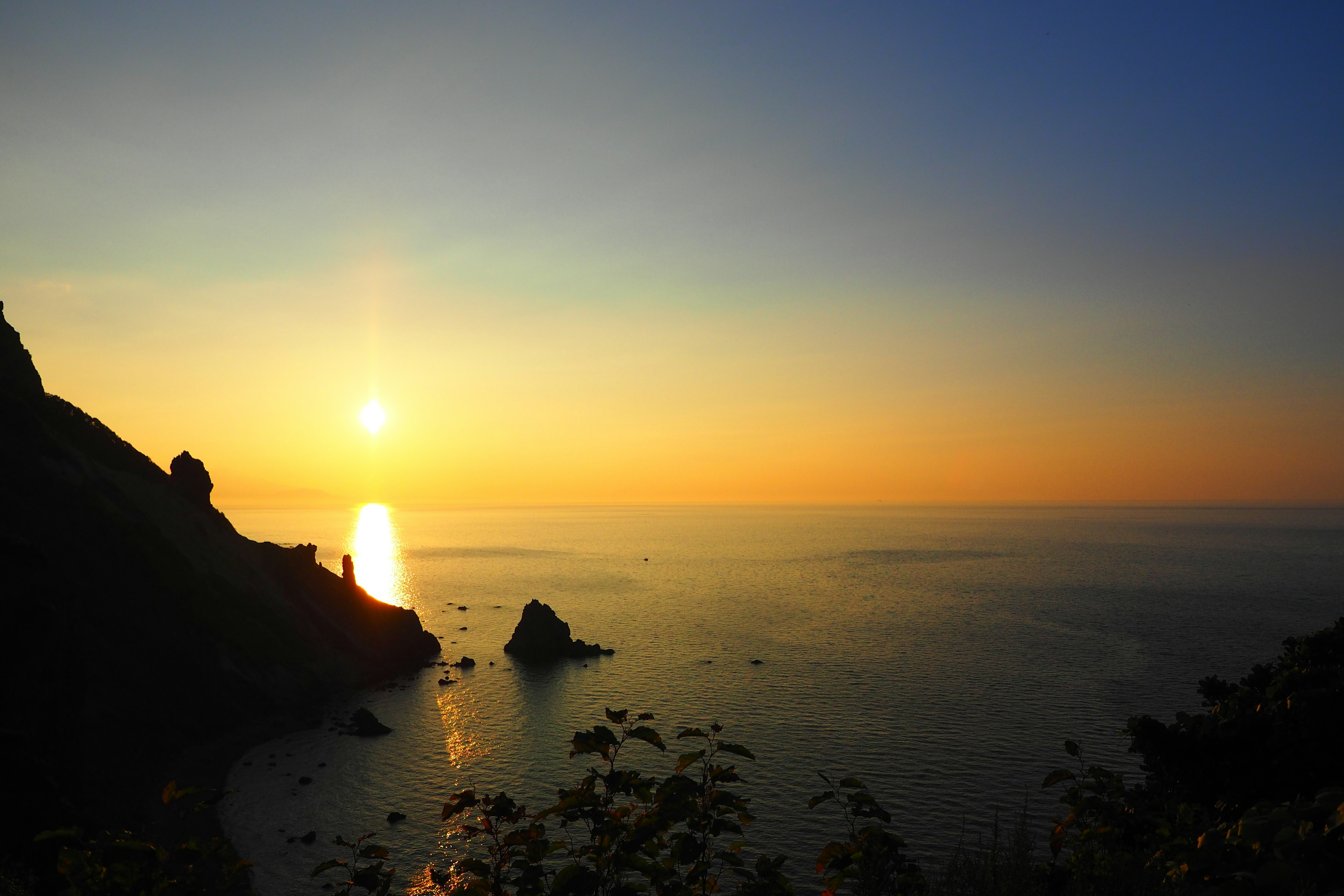 Schöner Sonnenuntergang über dem Meer mit Bergsilhouetten