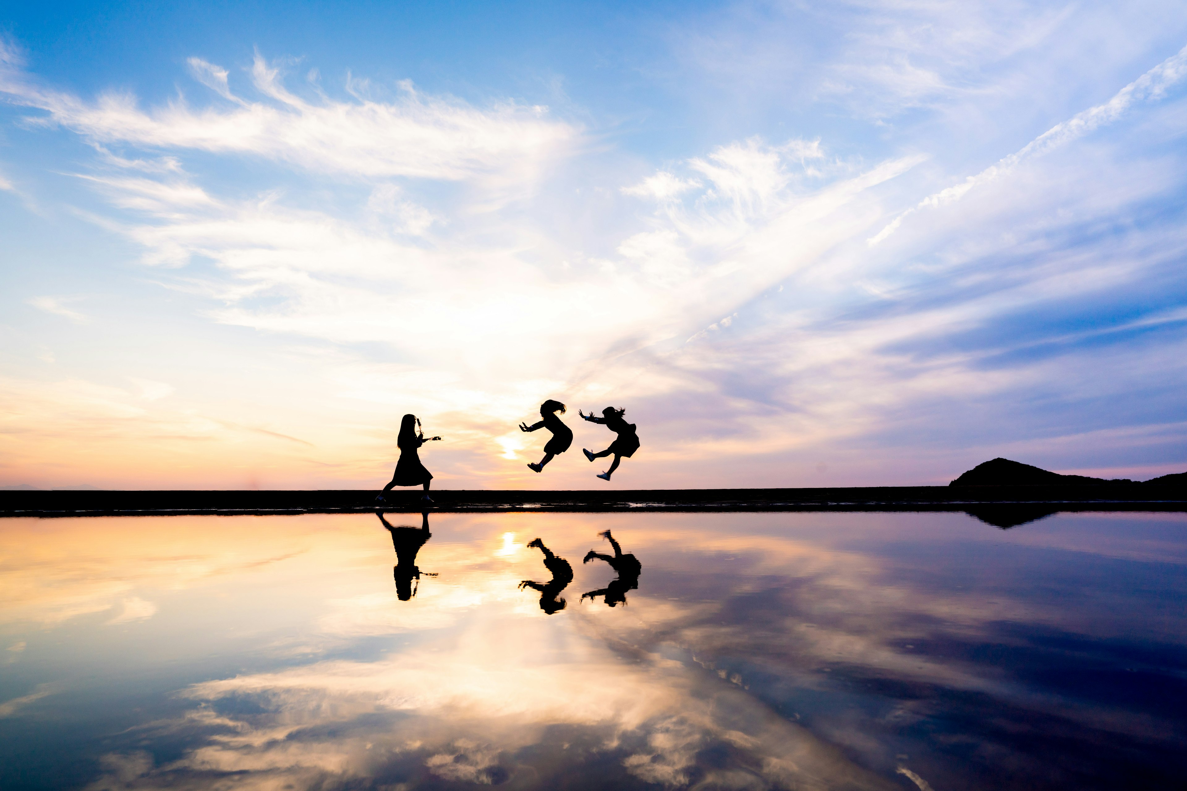 Silhouetten von Kindern, die unter einem Dämmerungshimmel mit Reflexionen spielen