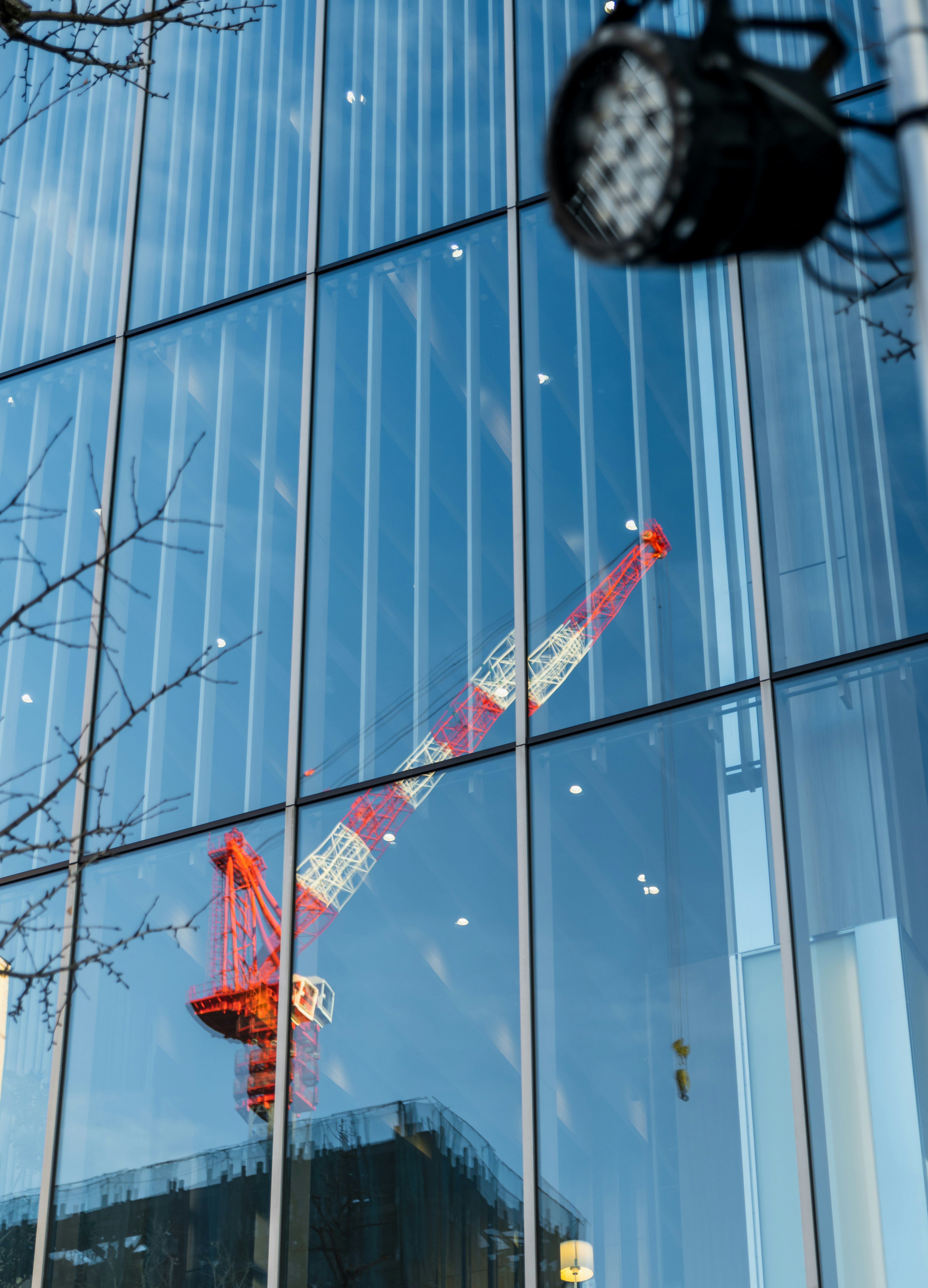 Red crane reflected in the glass facade of a building