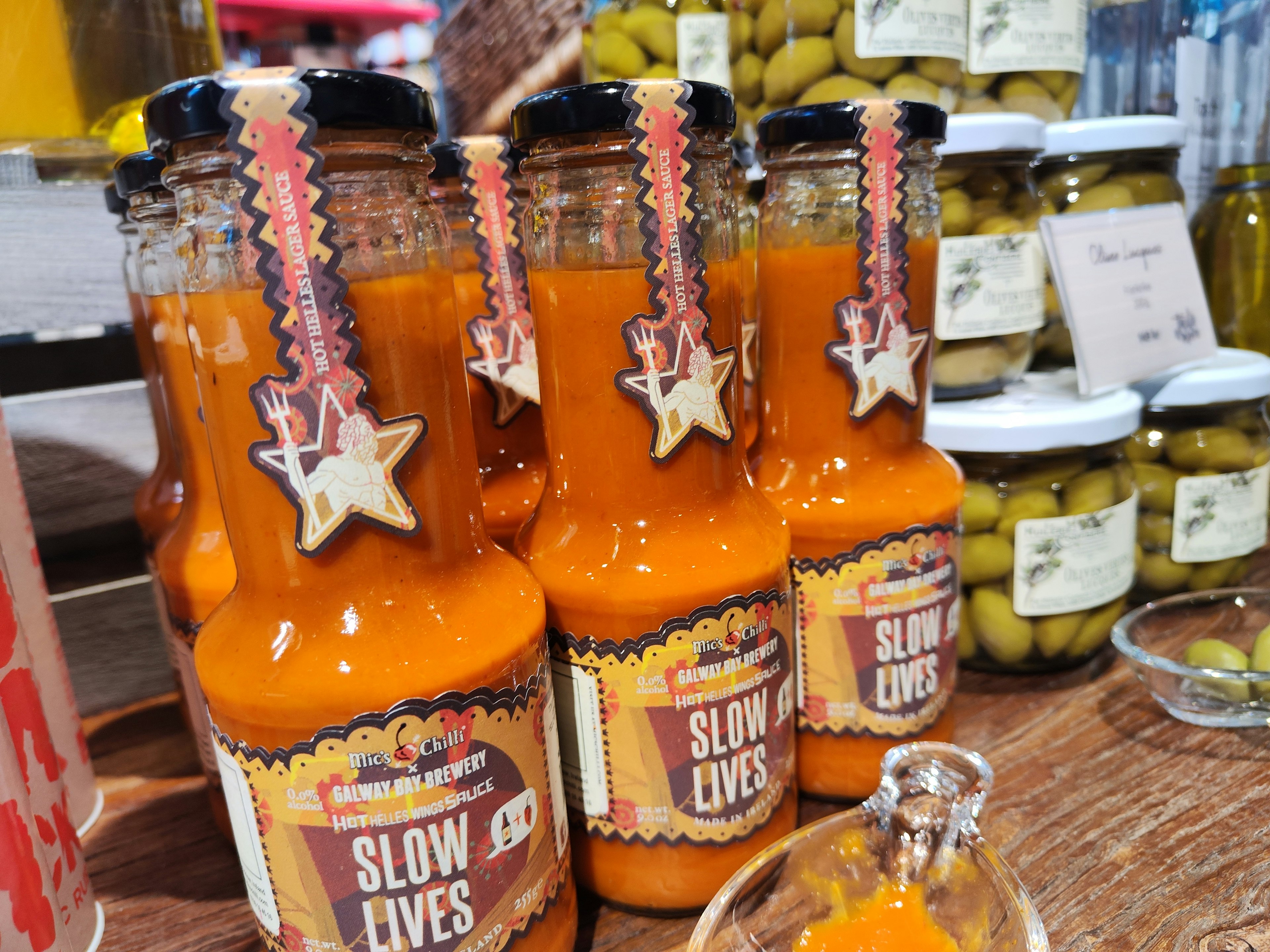 Scene with bottles of orange drink lined up featuring a label that says SLOW LIVES