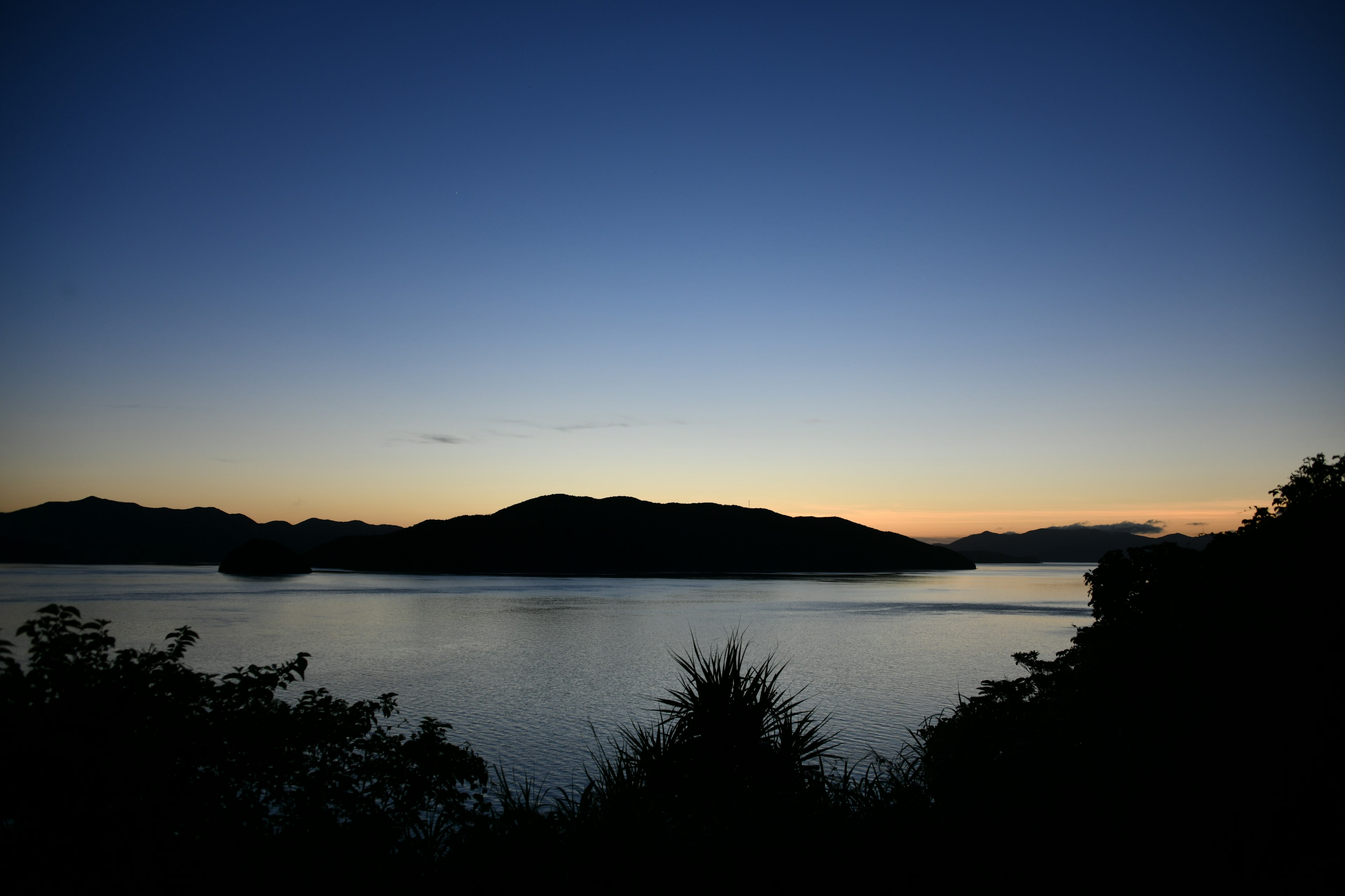 静かな湖と山のシルエットが見える夕暮れの風景