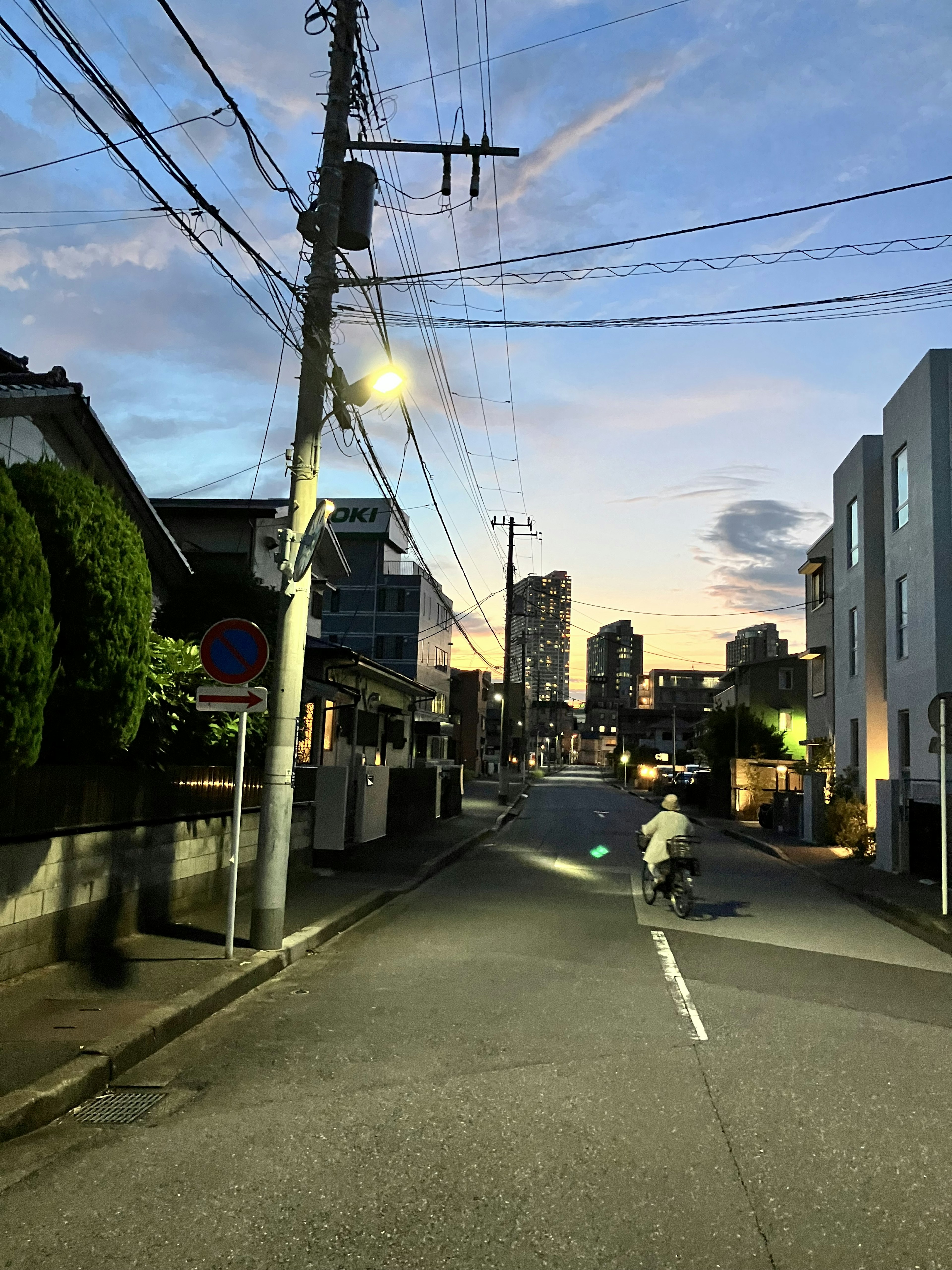 夕暮れ時の街並みに自転車に乗る人物がいる