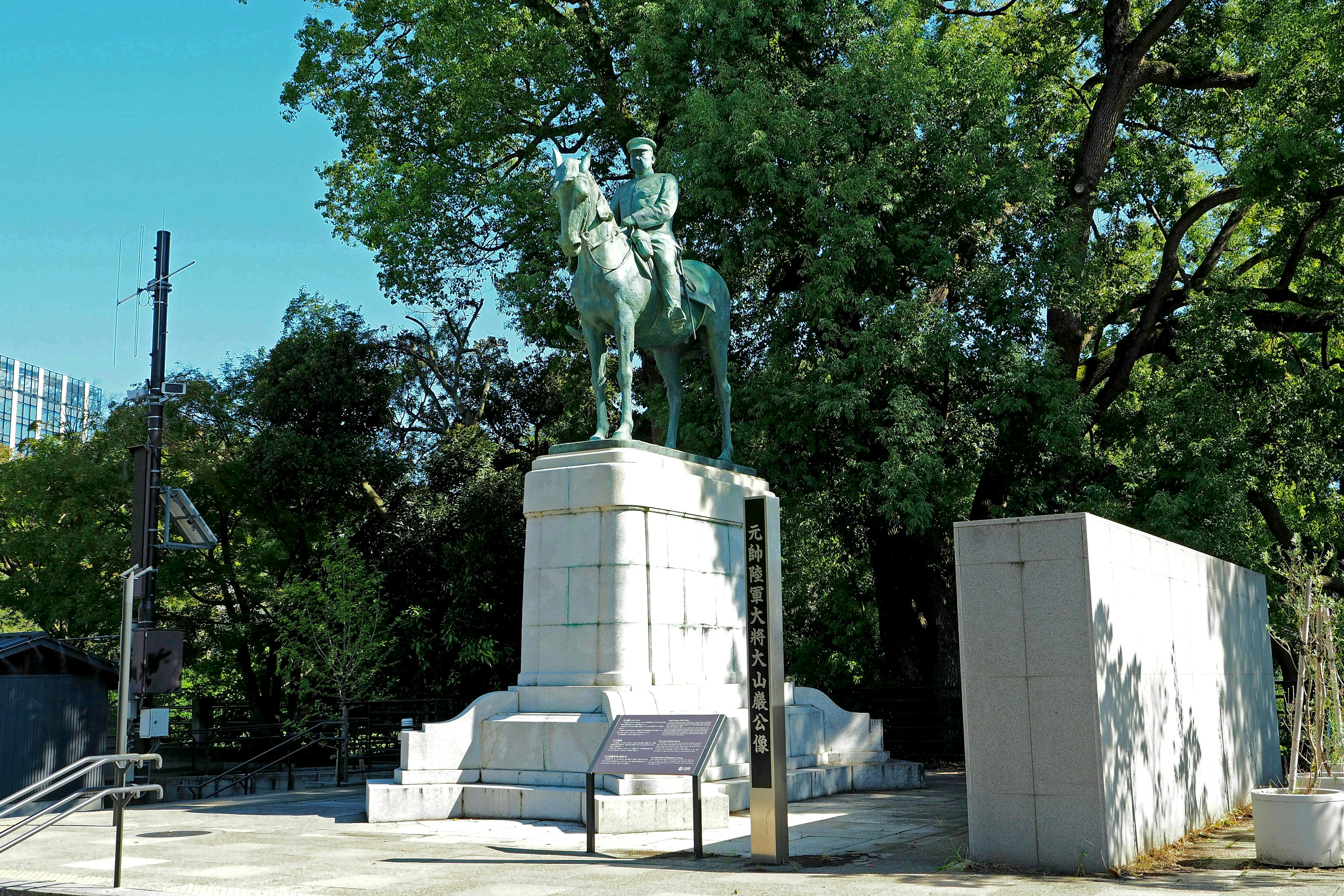 Equestrian statue under blue sky with lush green background