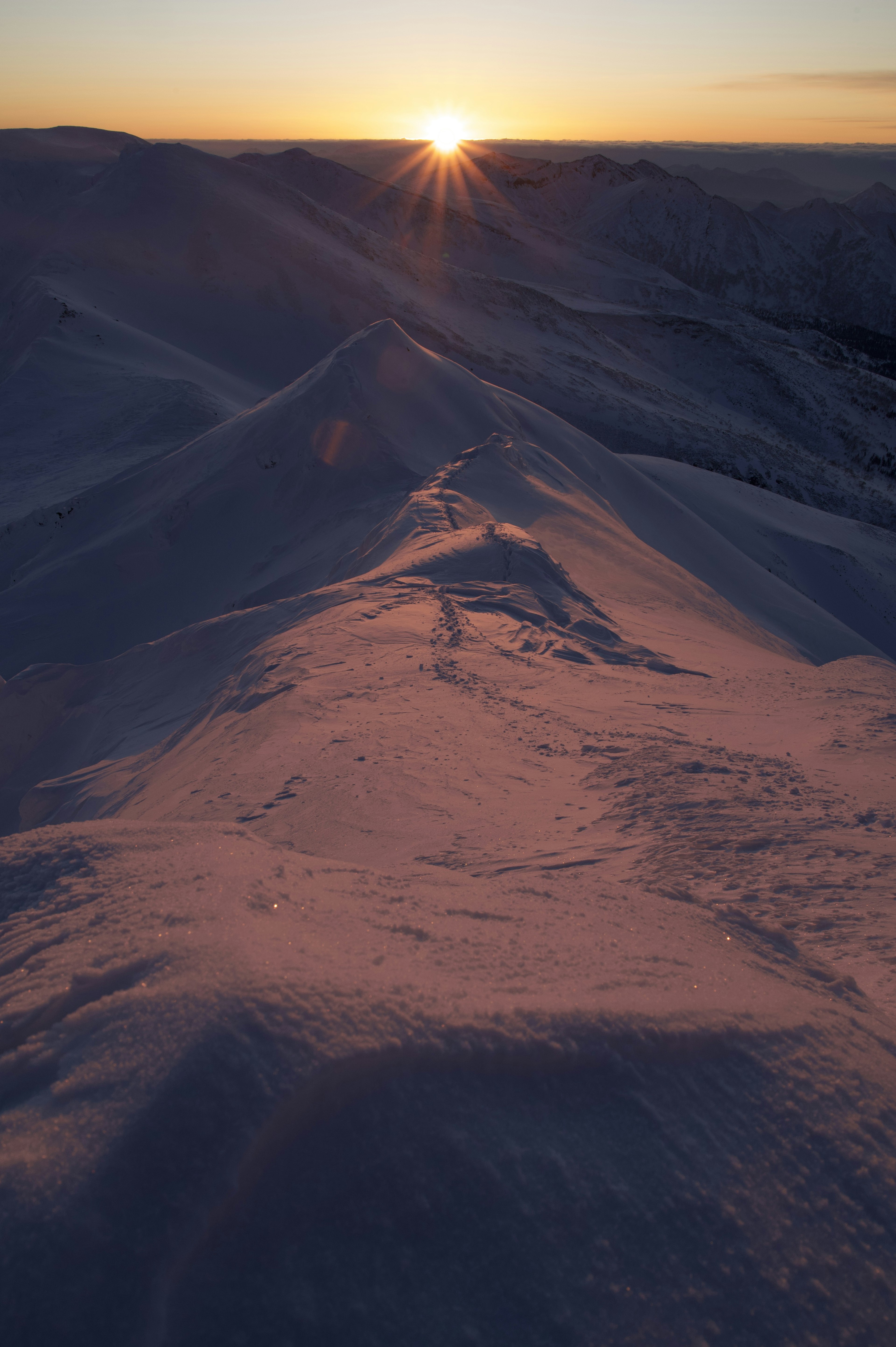 雪に覆われた丘と夕日が輝く風景