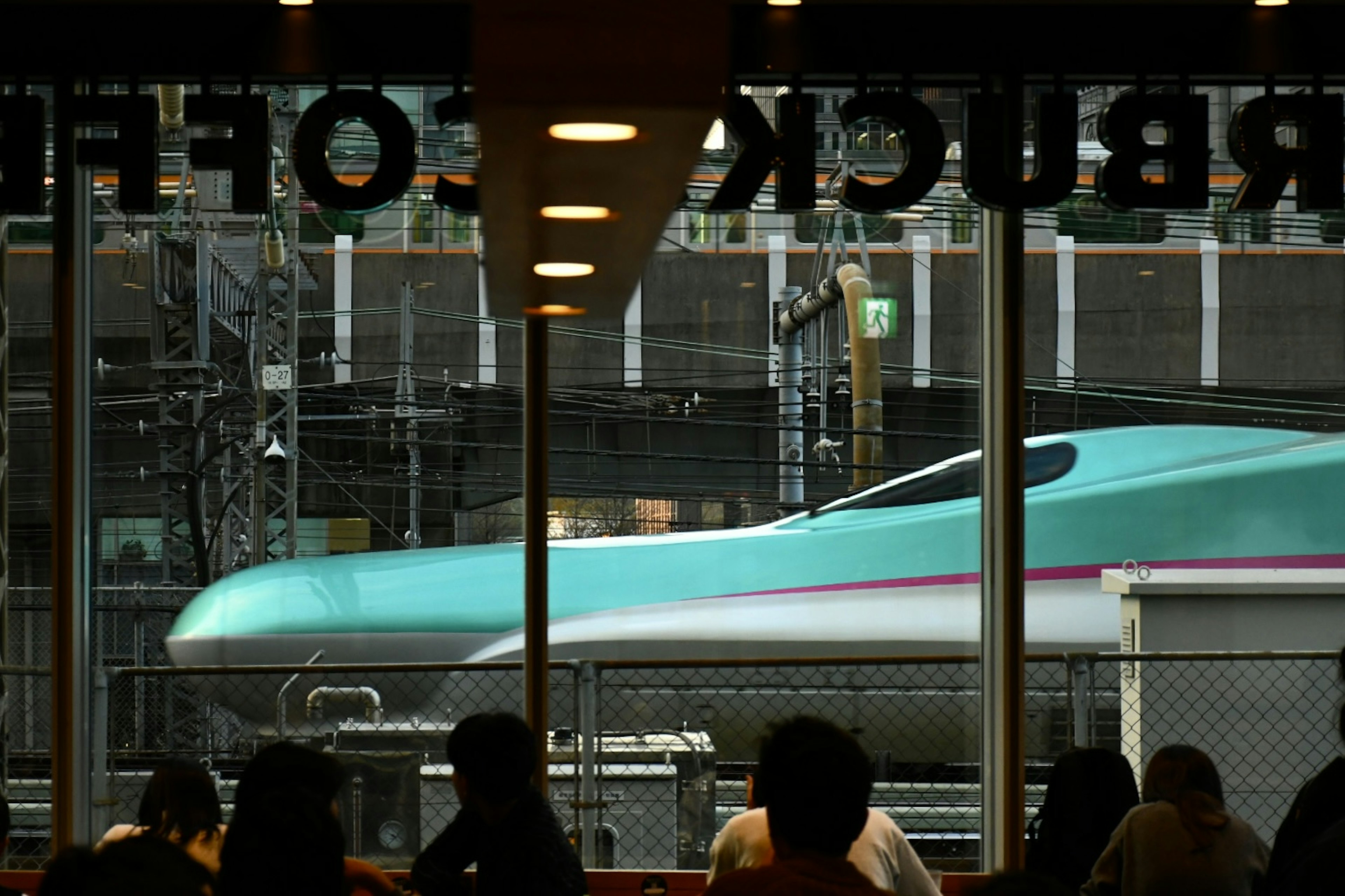 View of a Shinkansen train from a Starbucks window with people inside