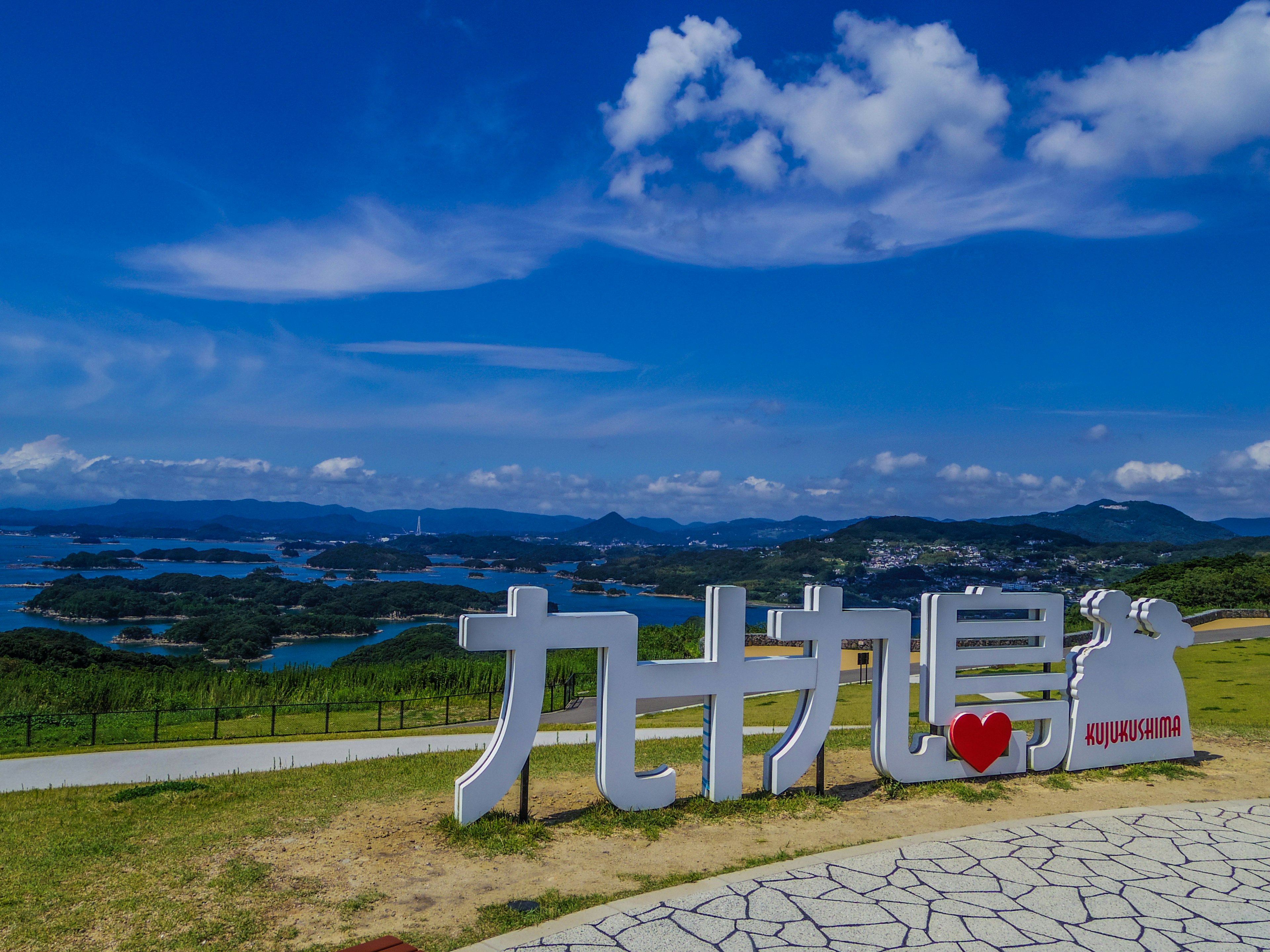 Tanda untuk Kujukushima di bawah langit biru yang cerah dengan pemandangan