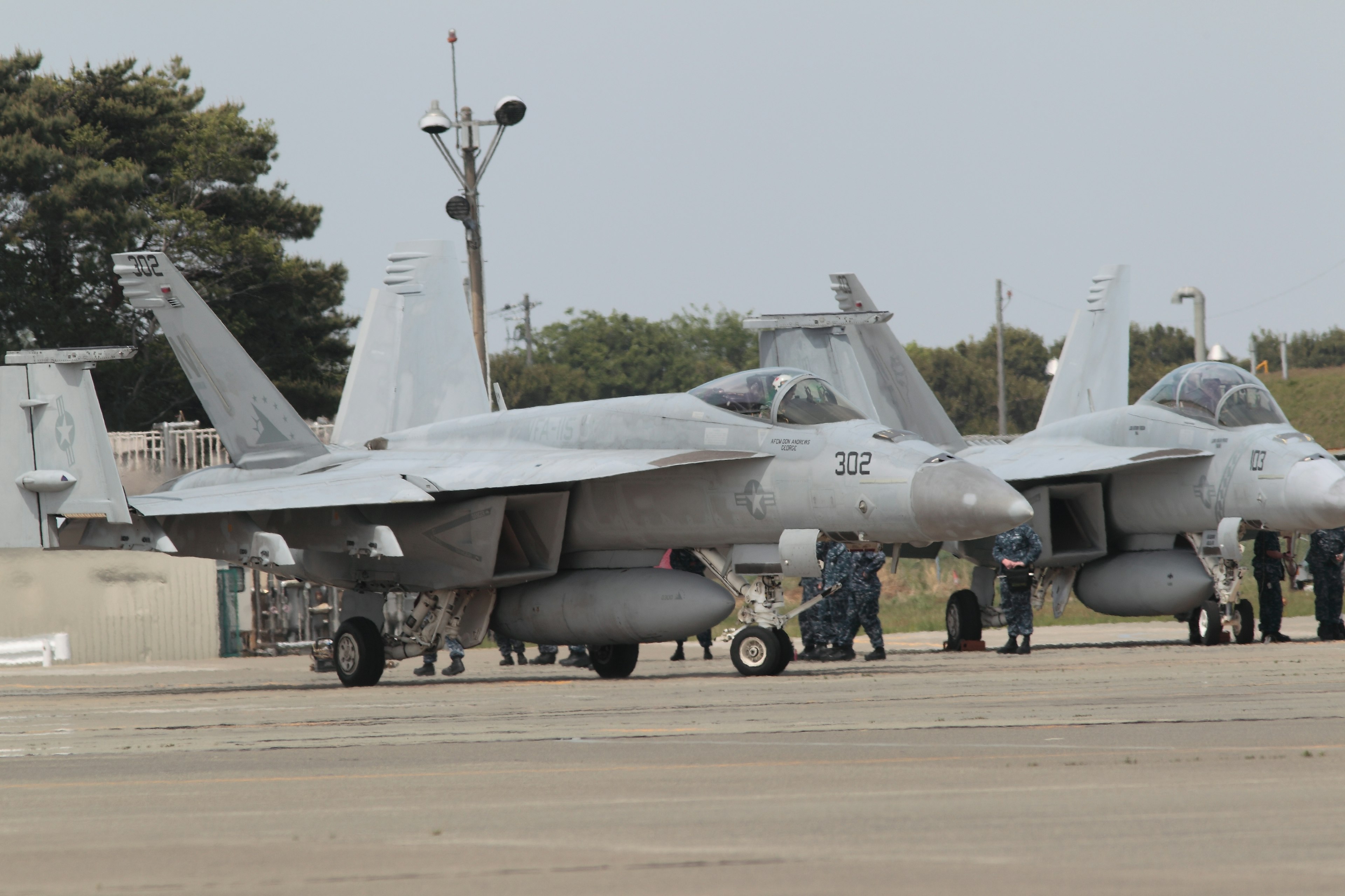 Des chasseurs F/A-18 alignés sur la piste avec une équipe de maintenance