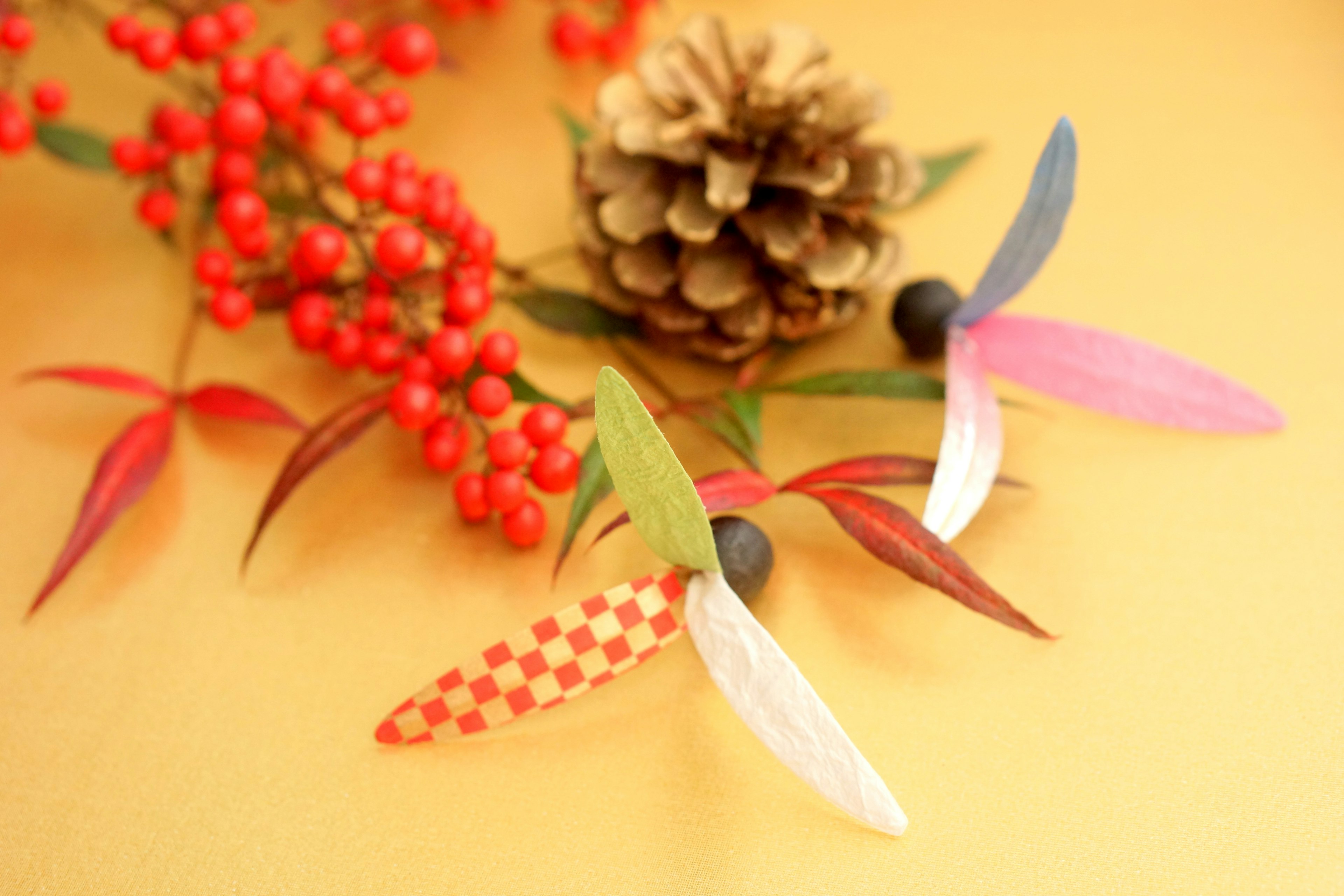 Hojas coloridas y elementos decorativos sobre un cono de pino y bayas rojas