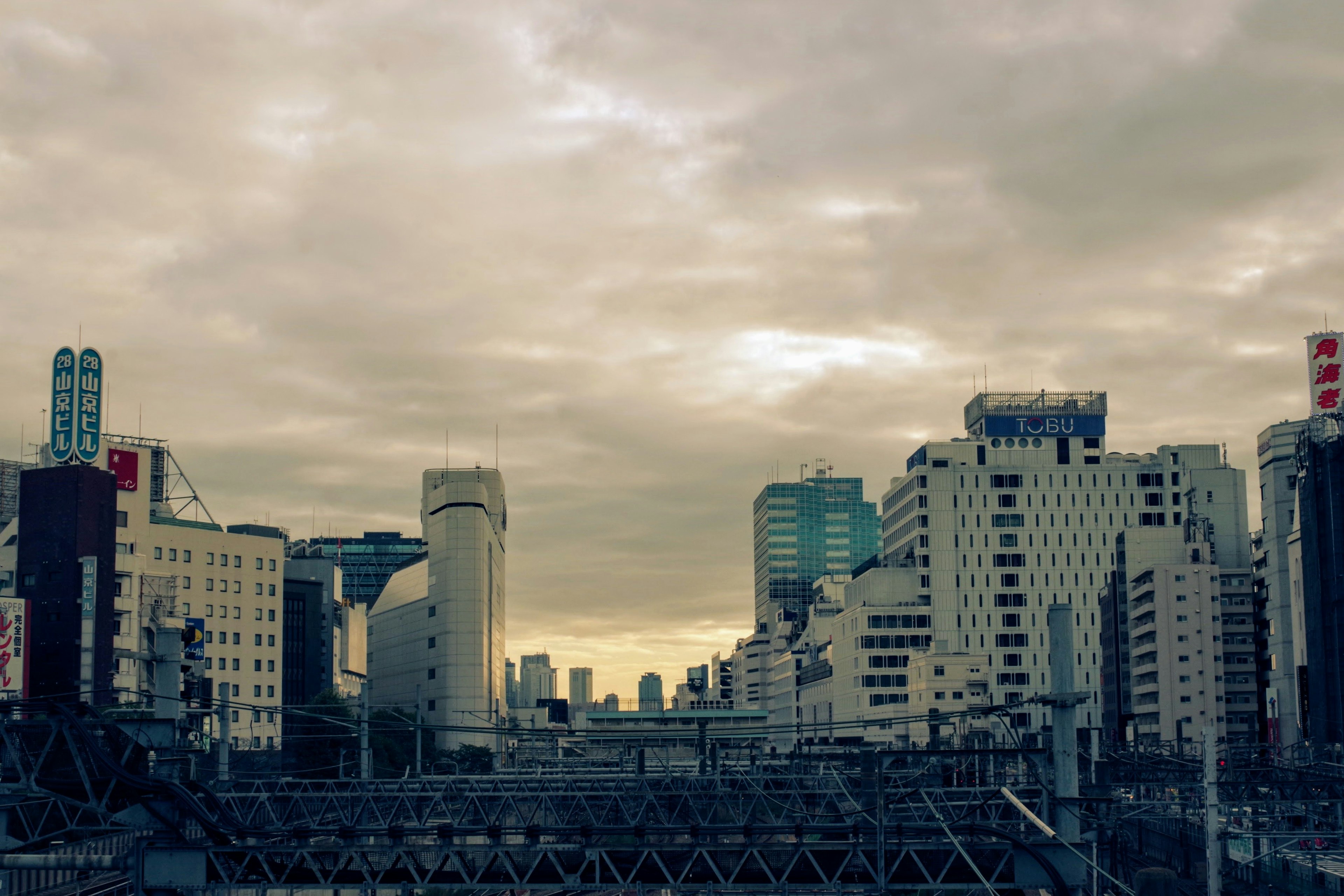 曇り空の下、都市の高層ビルが並ぶ風景