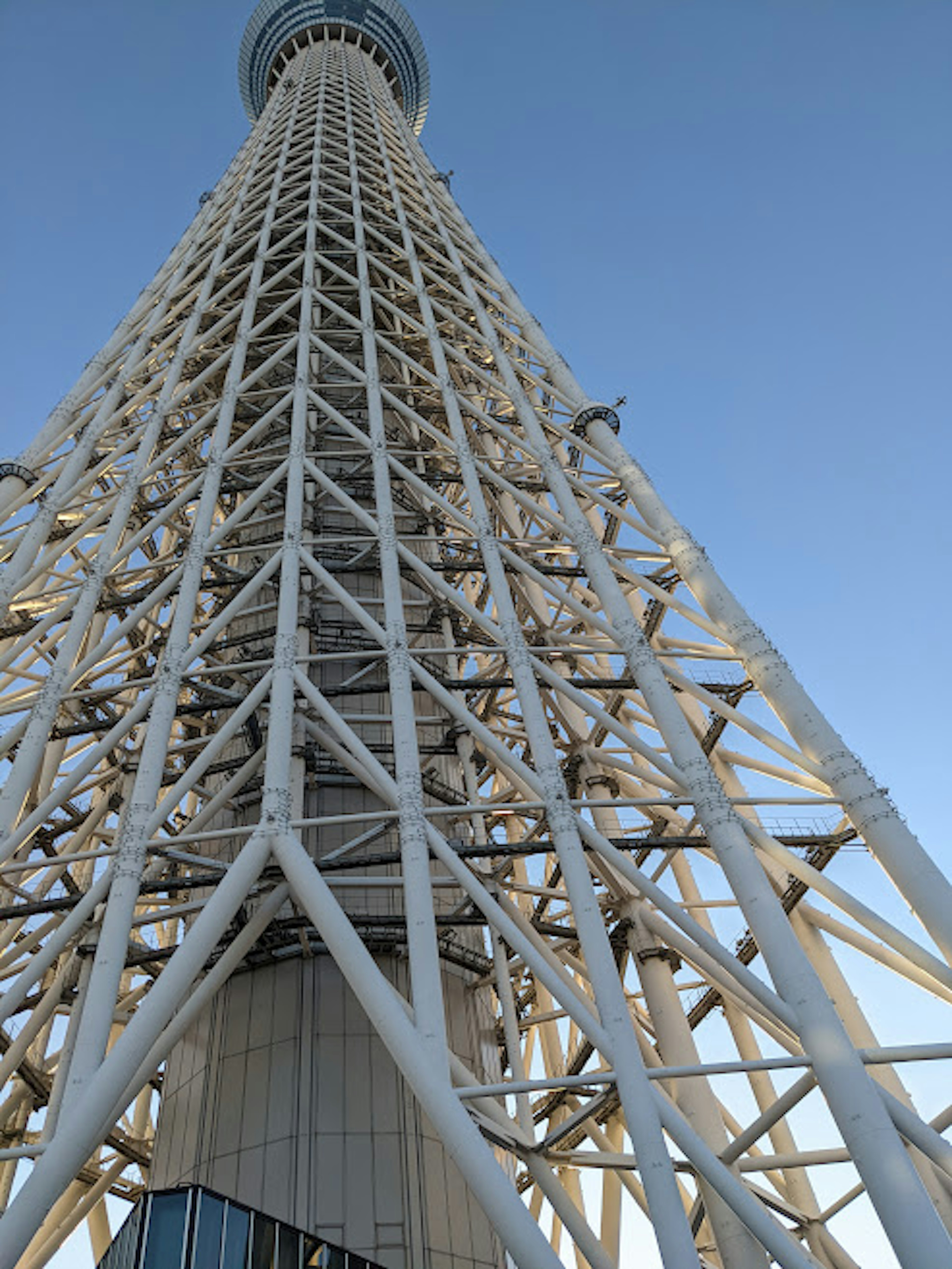 Foto Tokyo Skytree dilihat dari bawah yang menampilkan struktur baja putih