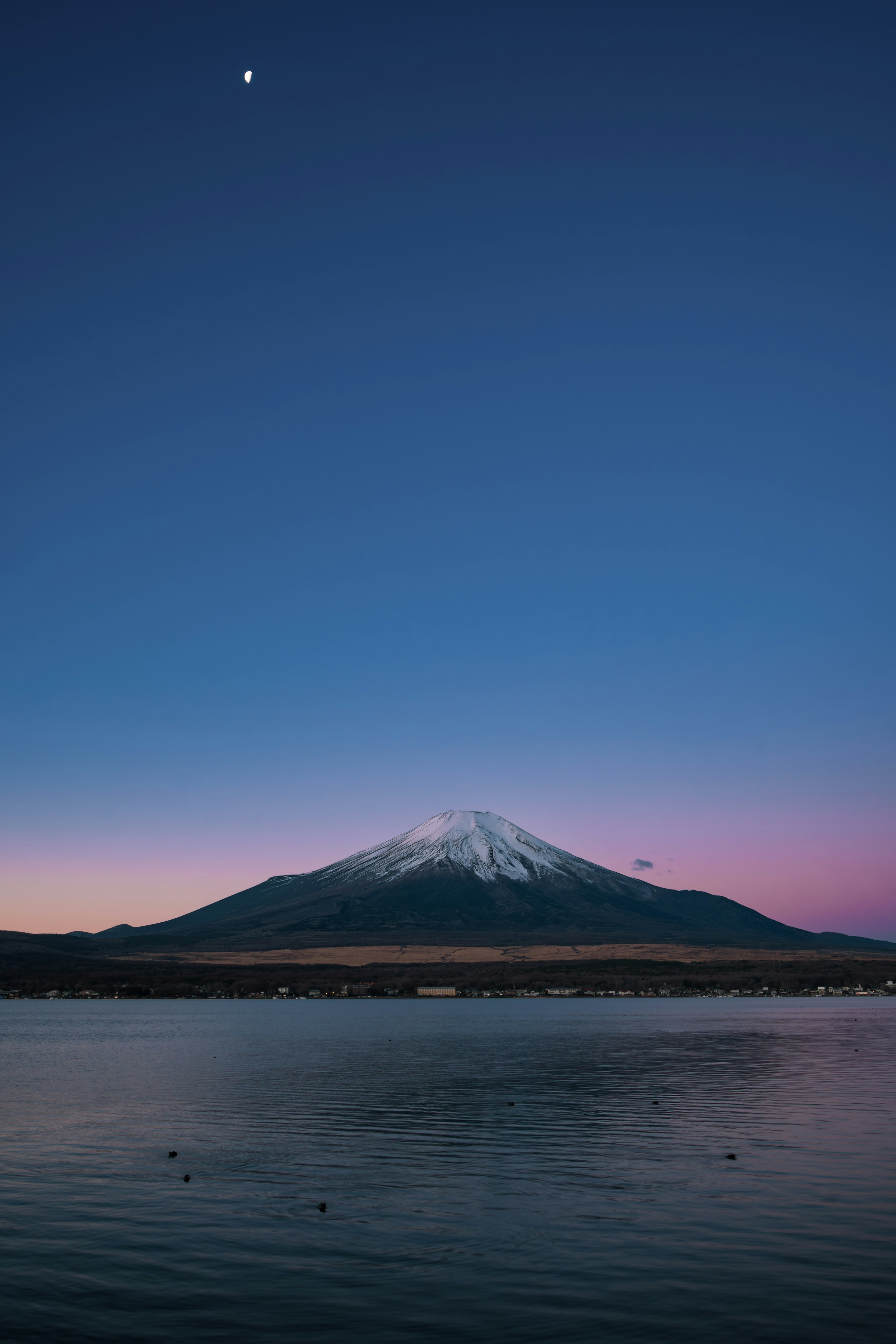 Hermosa vista del monte Fuji de noche con reflejo en el lago y luz de luna en el cielo azul