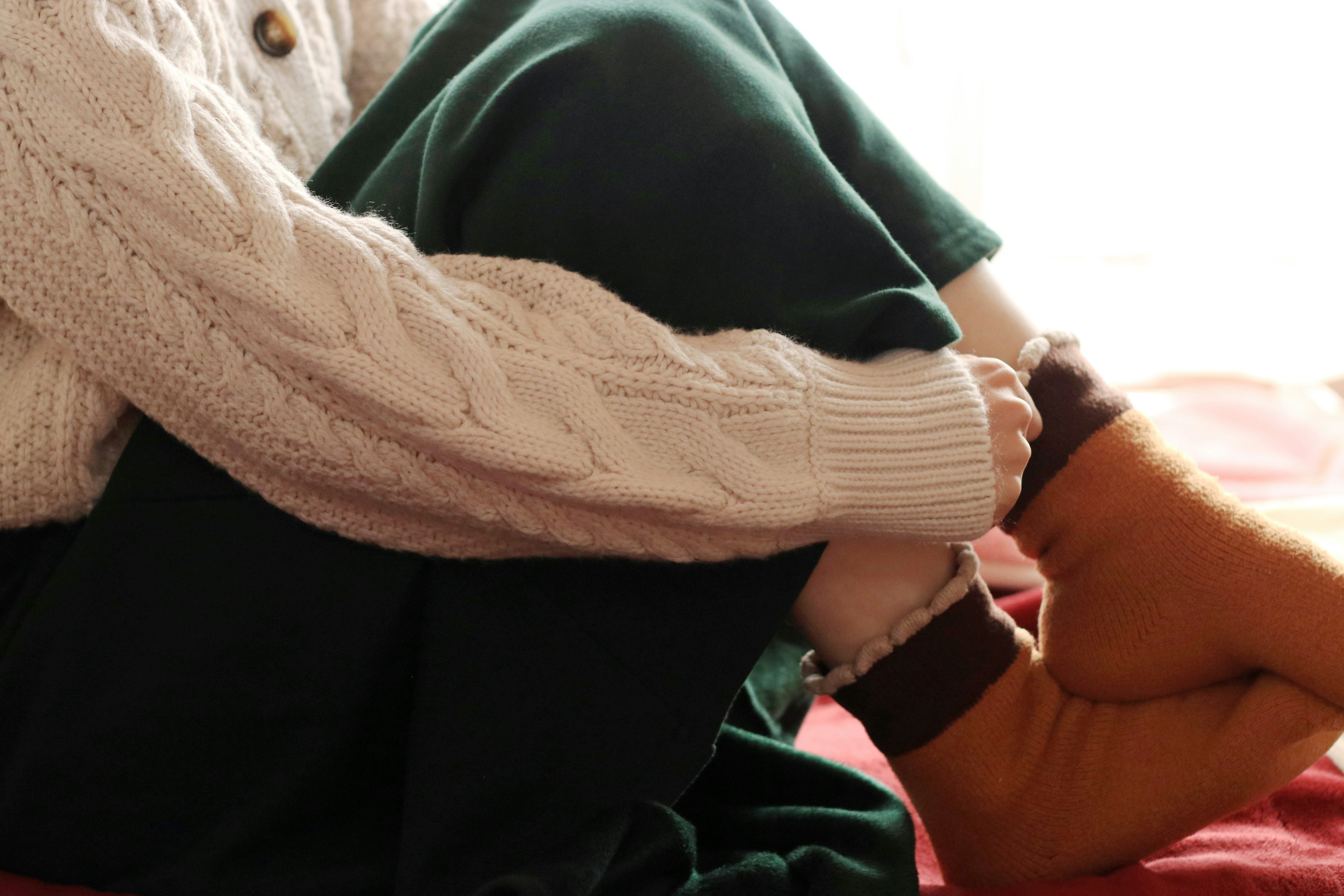 A person sitting with crossed legs wearing a cozy sweater and boots