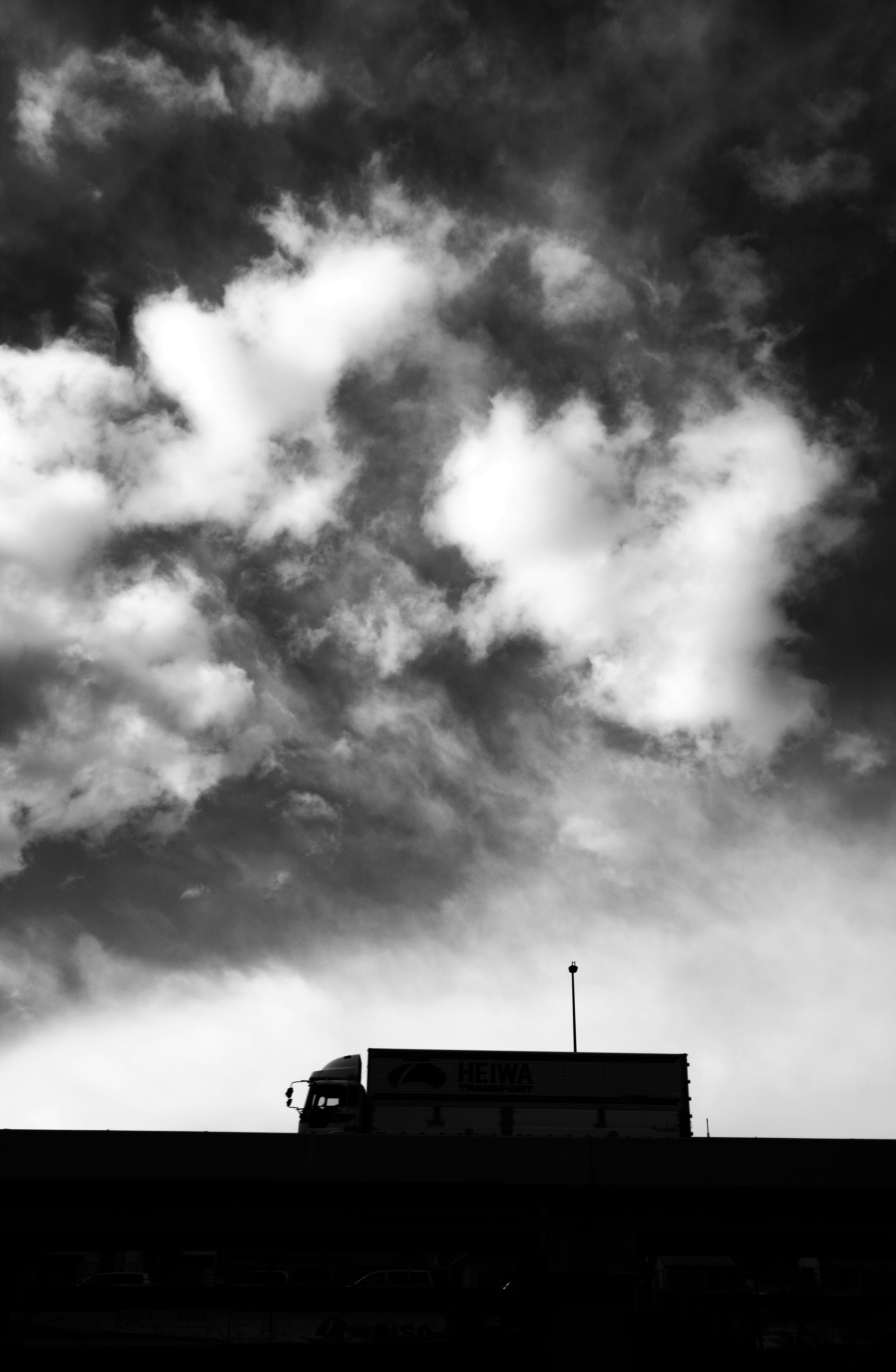 Silhouette of a truck against a dramatic black and white sky with clouds