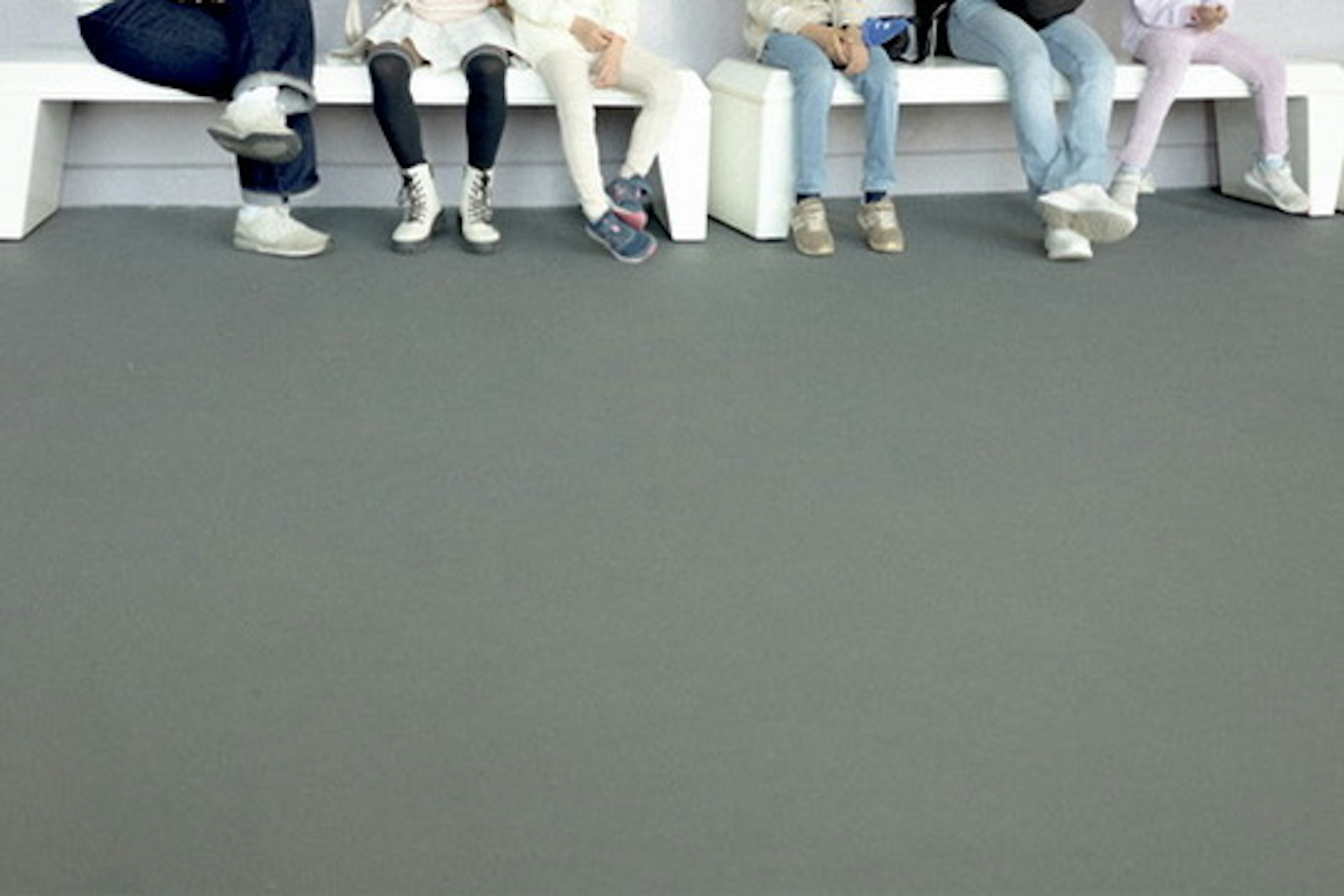 Photo of several people sitting with visible feet in a modern waiting area