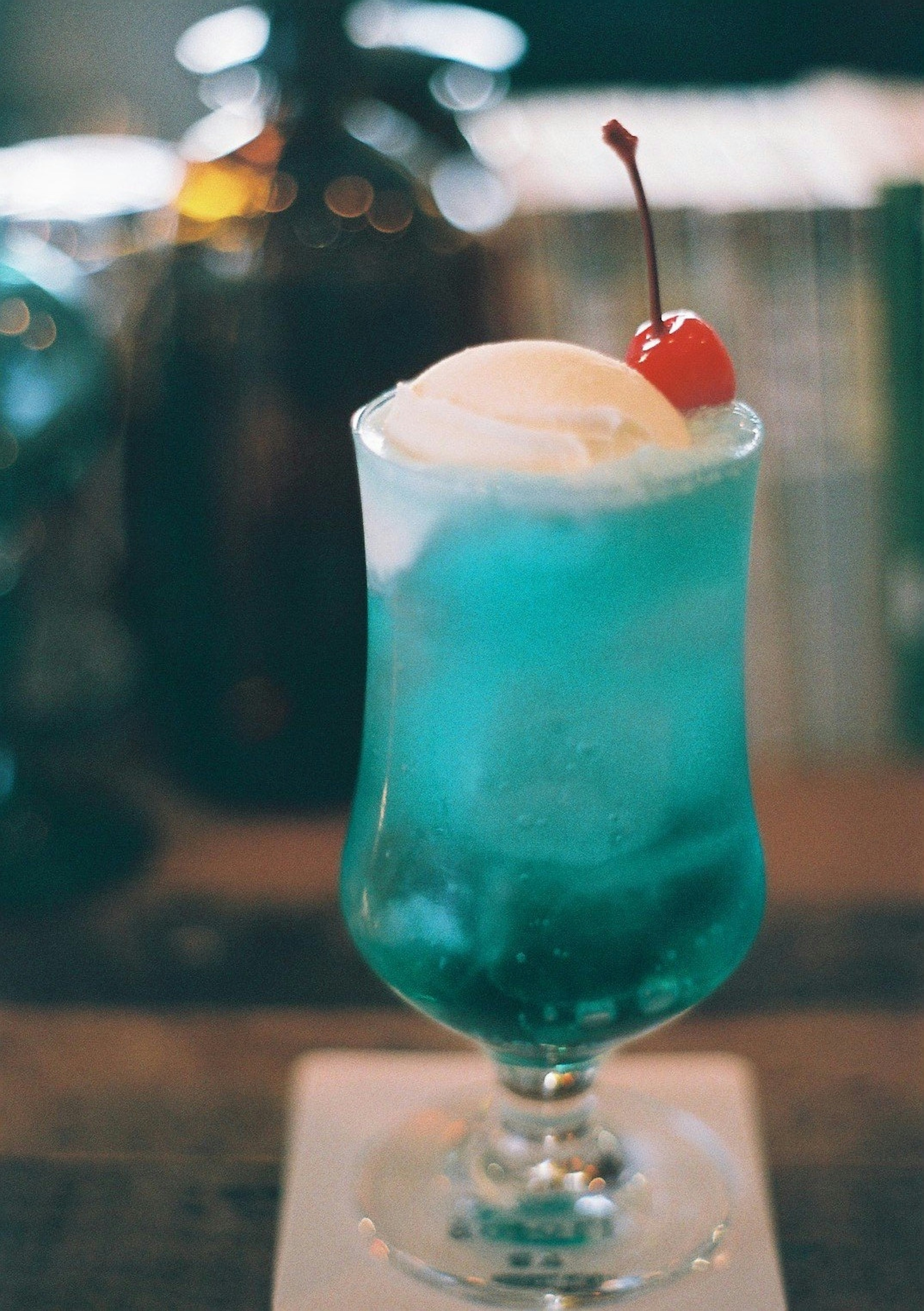 Blue cocktail topped with ice cream and a cherry