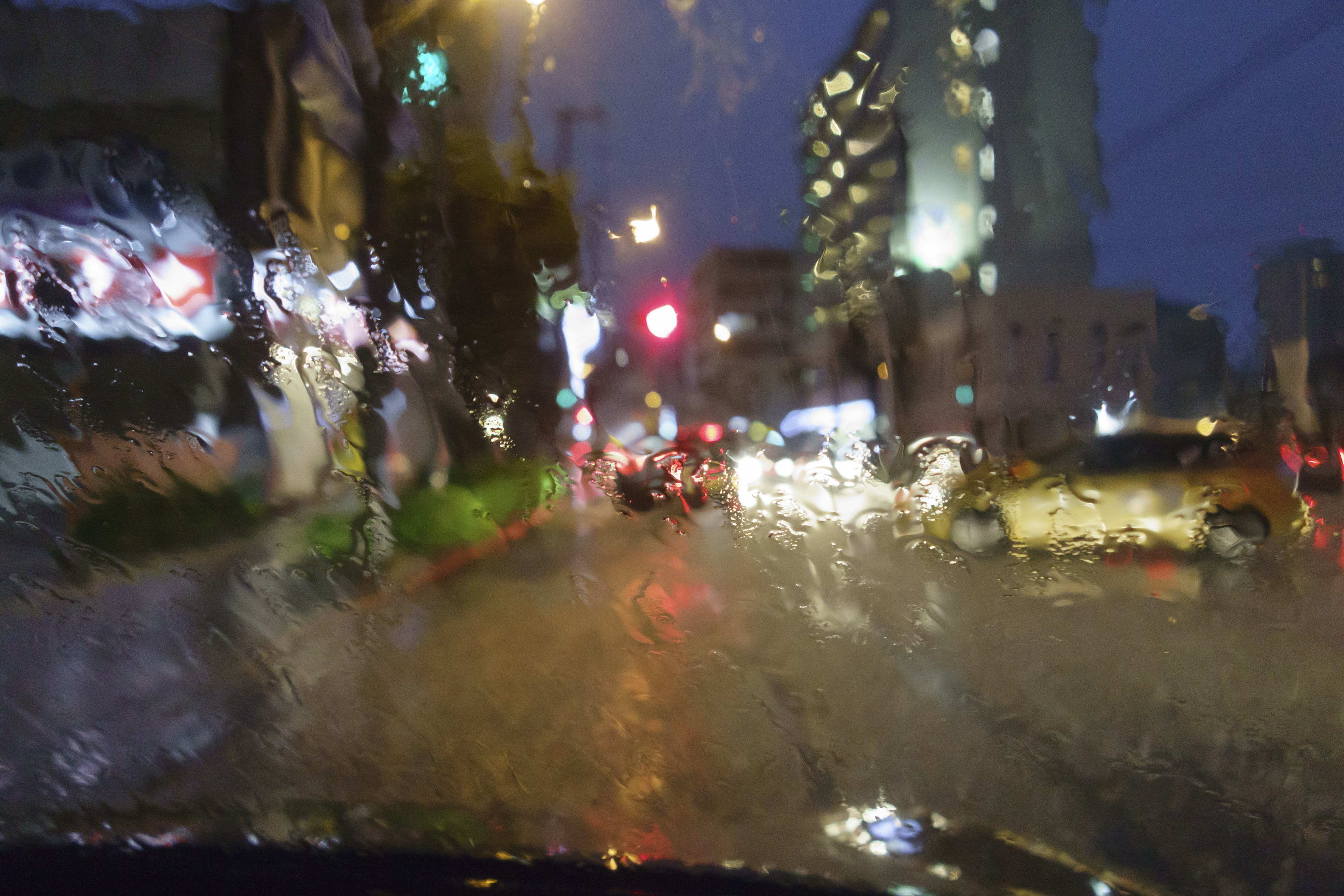 Blurred cityscape in the rain featuring lights and moving cars