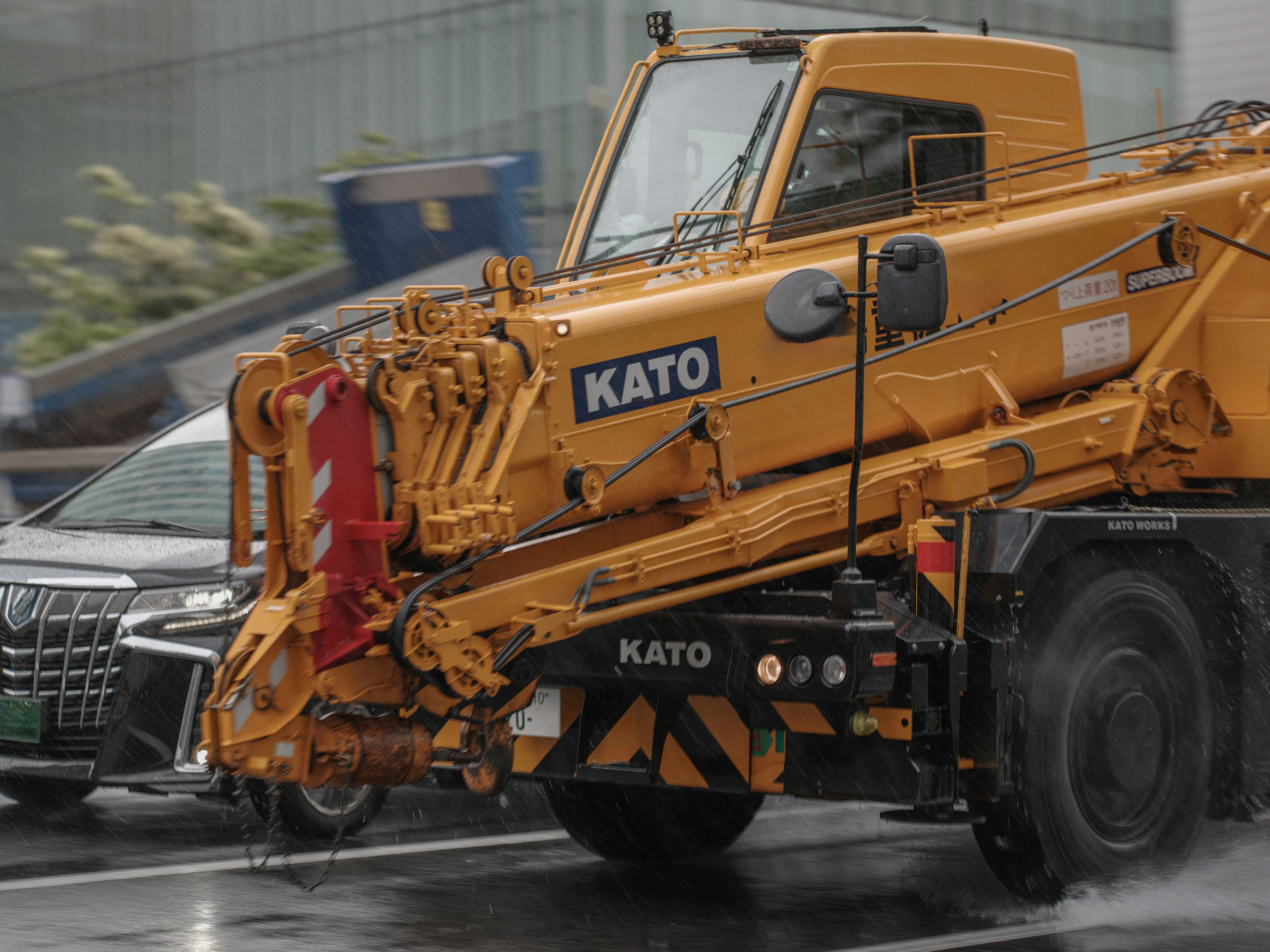 Camion grue jaune roulant sur une route mouillée