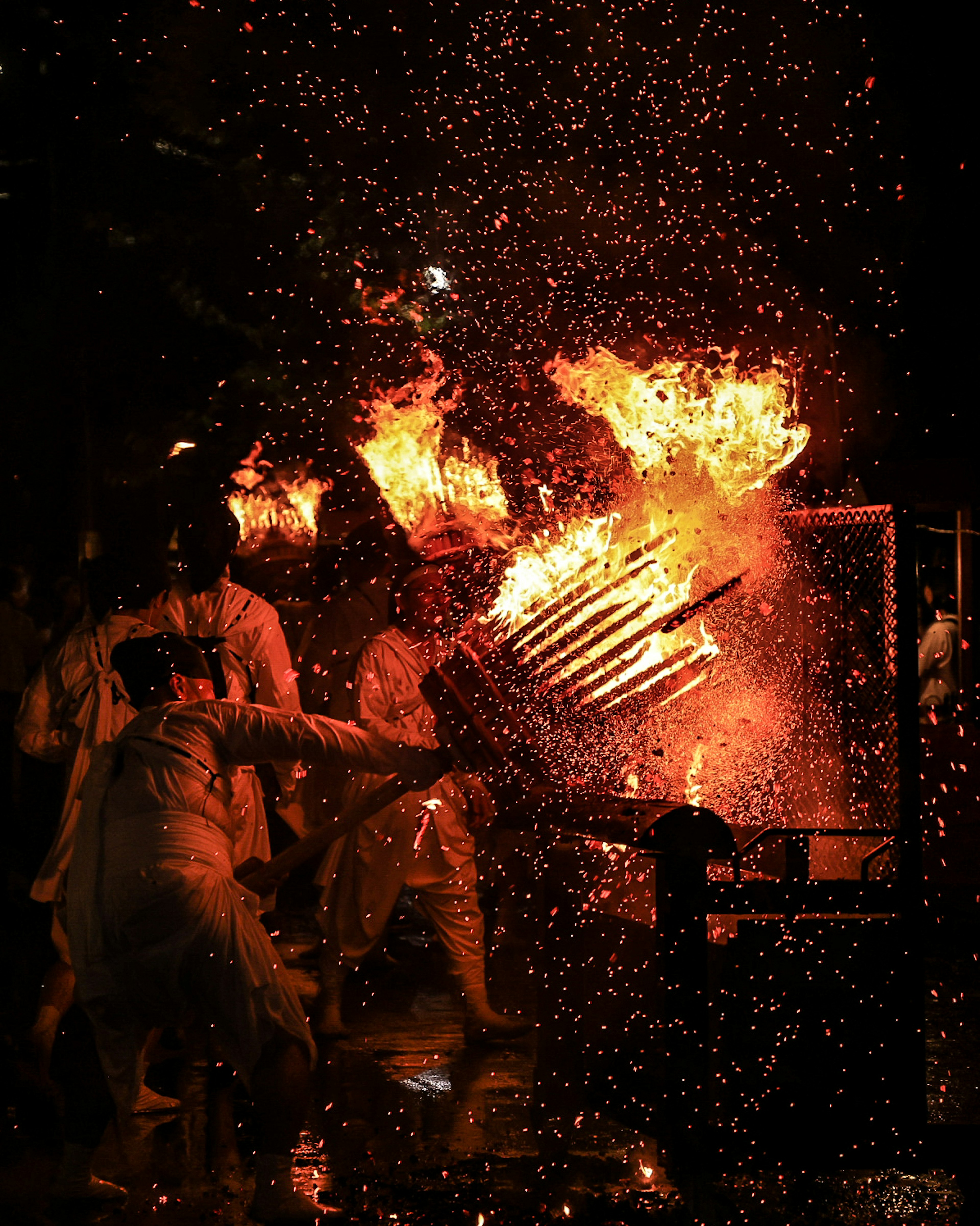 Escena de festival con personas sosteniendo llamas y chispas voladoras