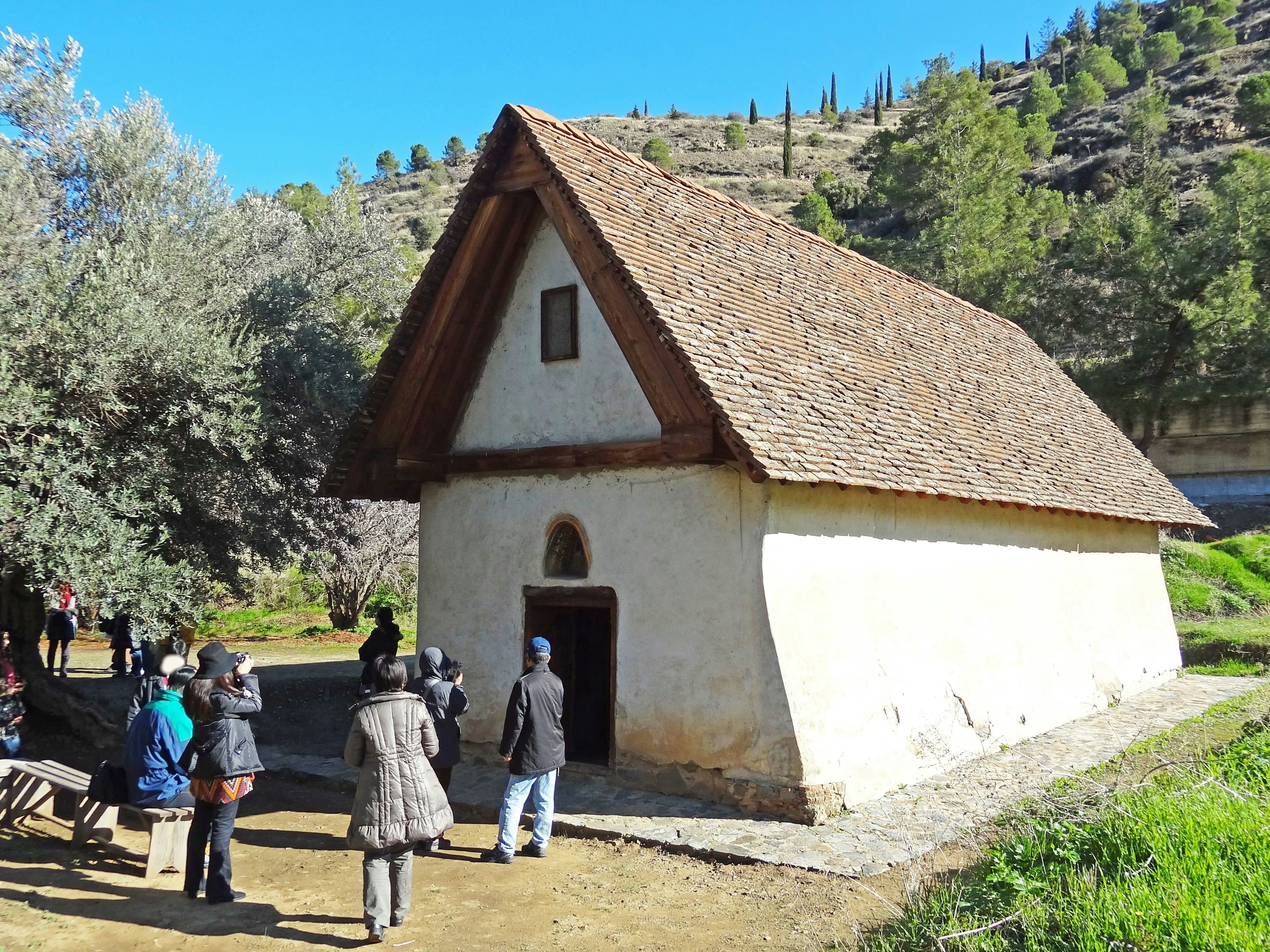 Group of people approaching an old house with a triangular wooden roof