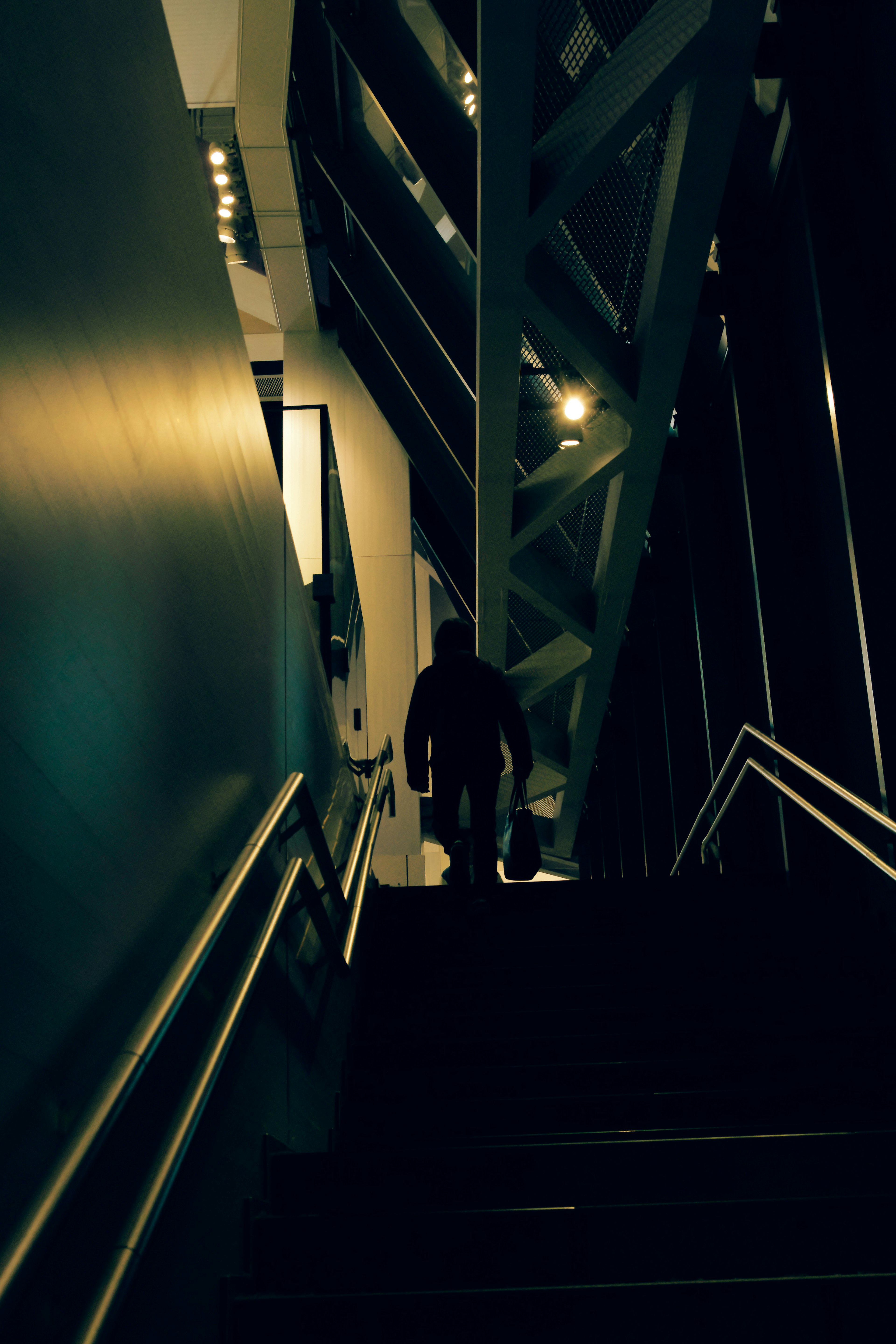 Silueta de una persona subiendo escaleras con un fondo de pared oscura