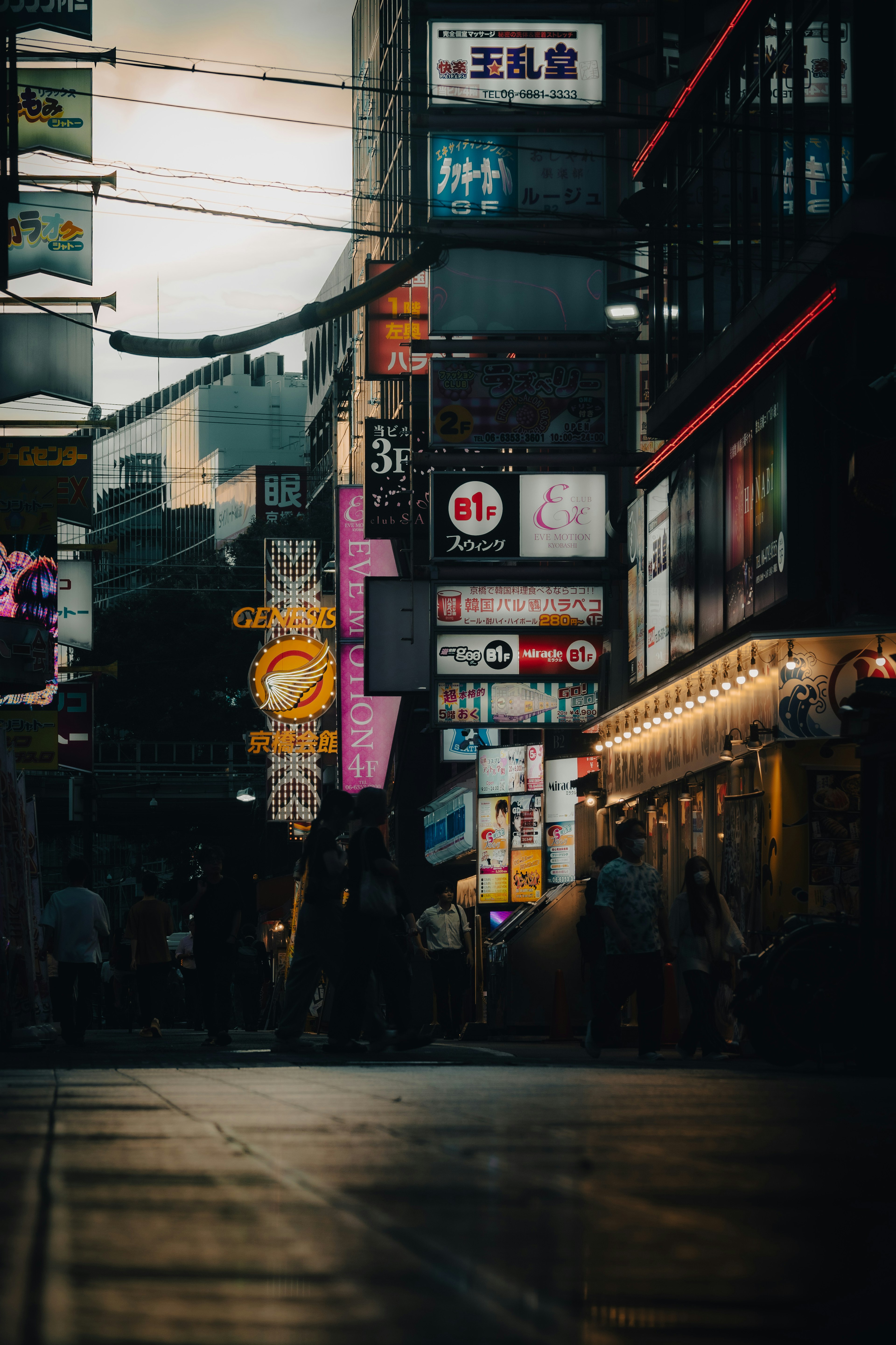 賑やかな街並みの夜景に、人々が行き交う様子と色とりどりの看板が映る