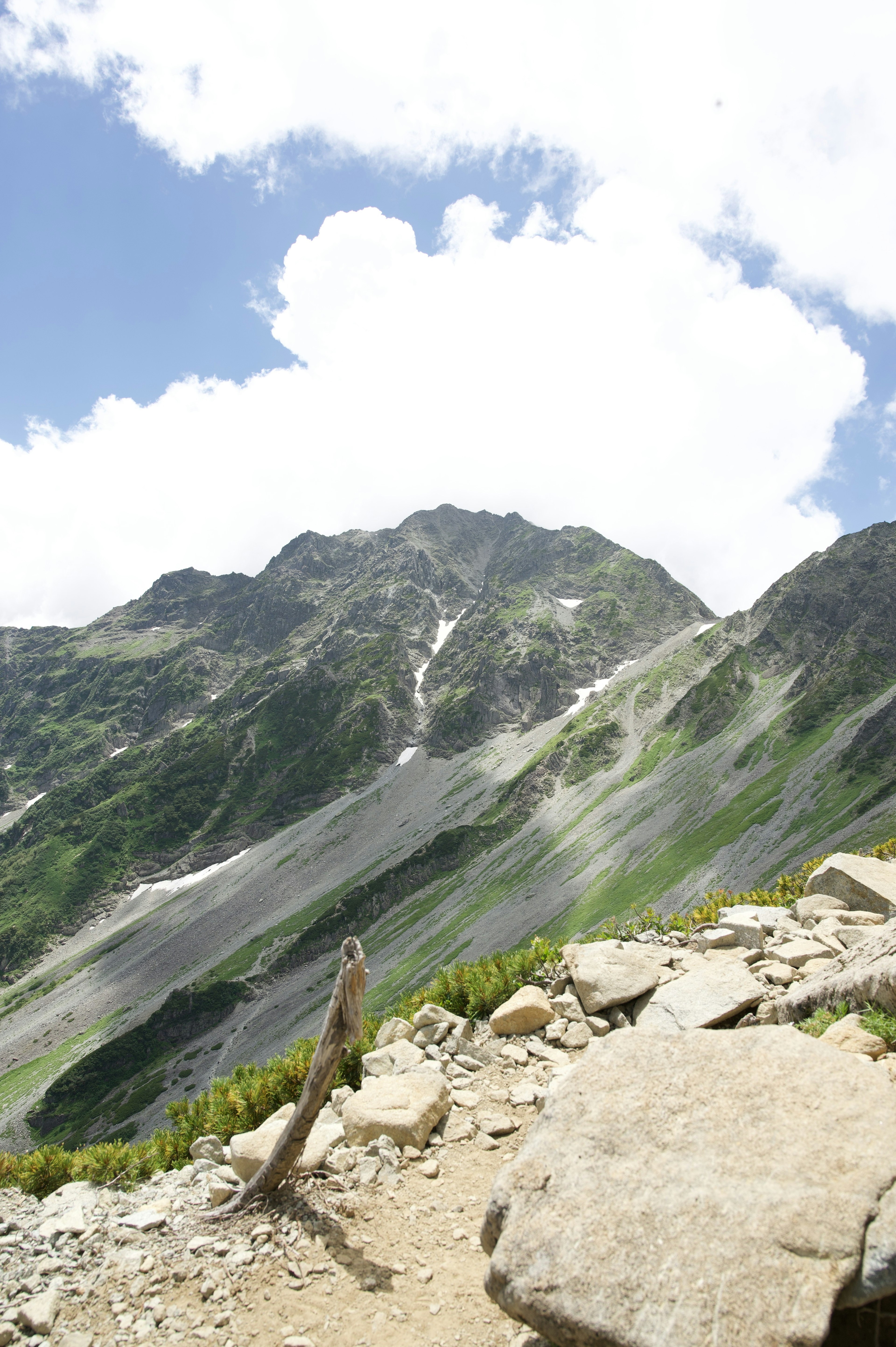 蓝天和云下的山脉风景，展现岩石和绿色植物