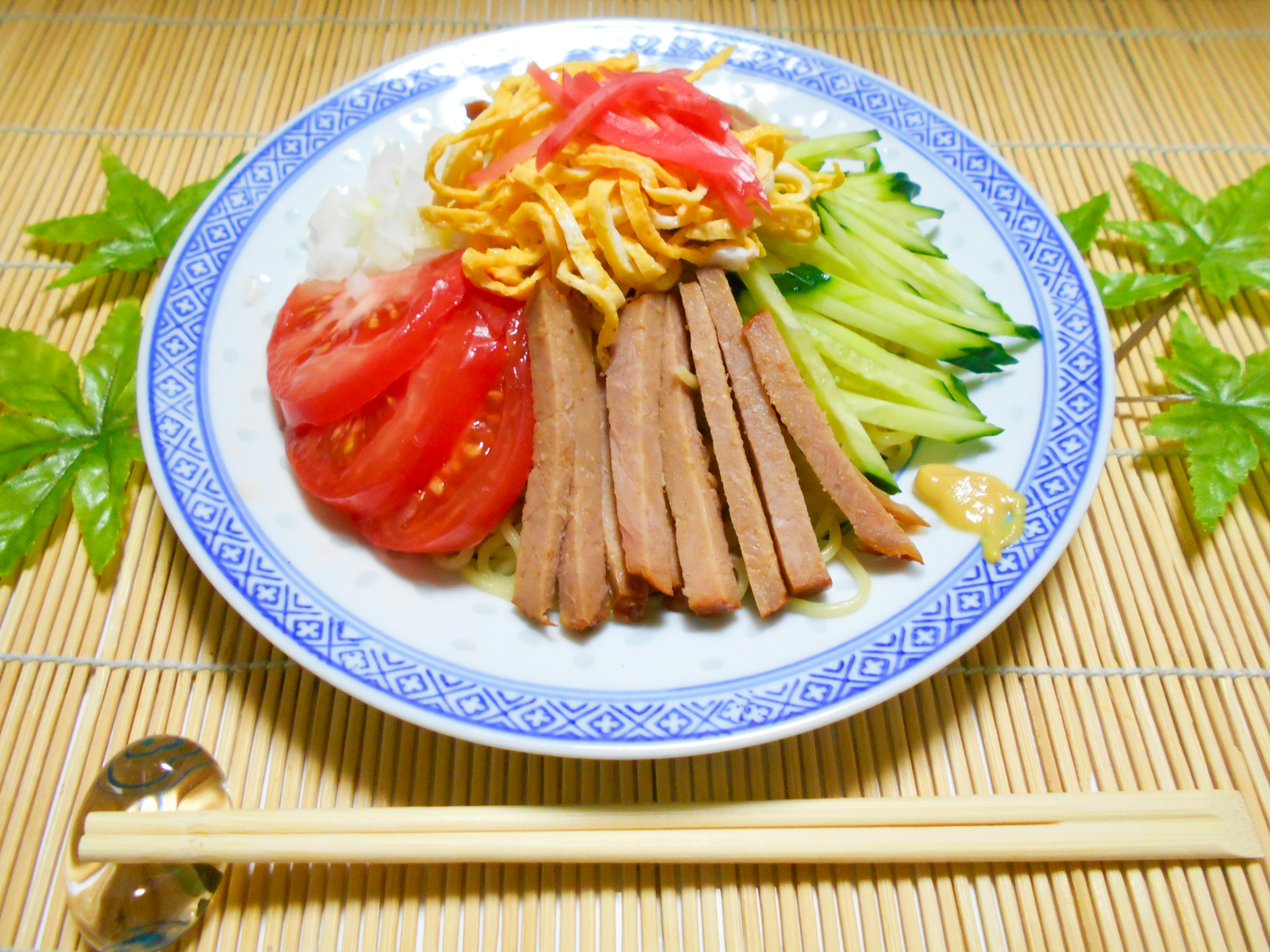 Colorful dish featuring sliced tomatoes, cucumbers, egg, and meat arranged beautifully