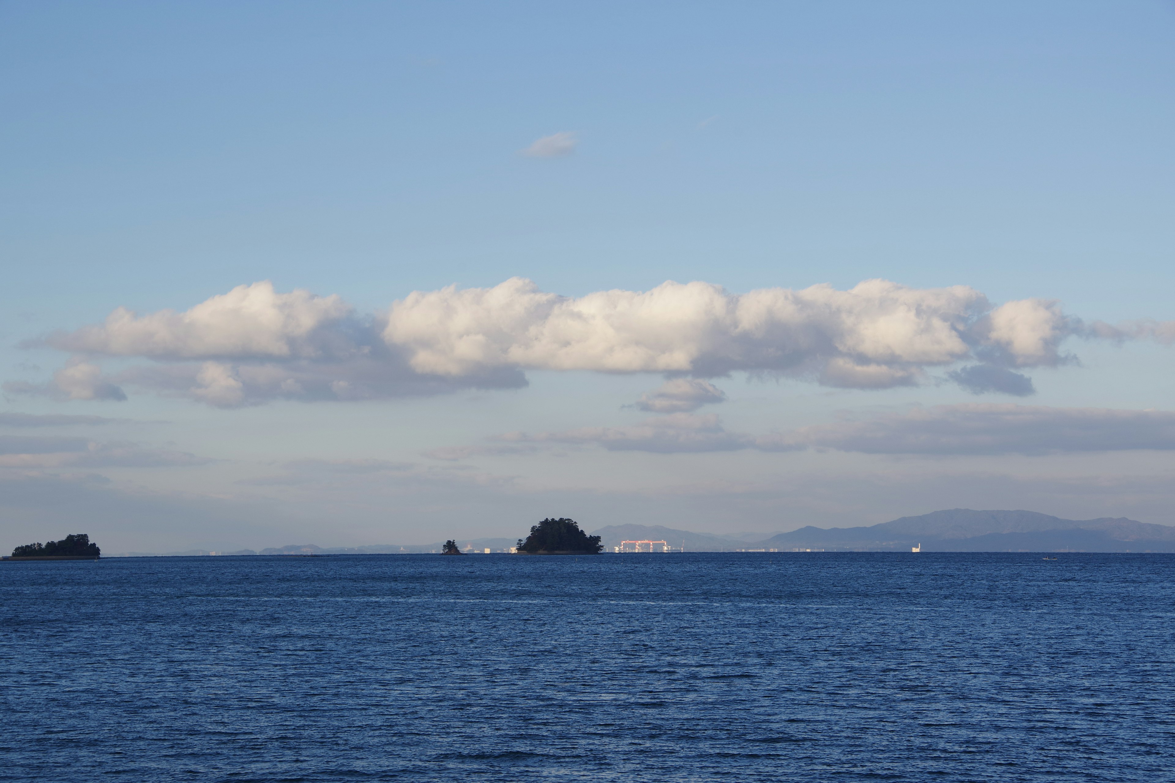 青い海と空に浮かぶ雲と小さな島々の風景