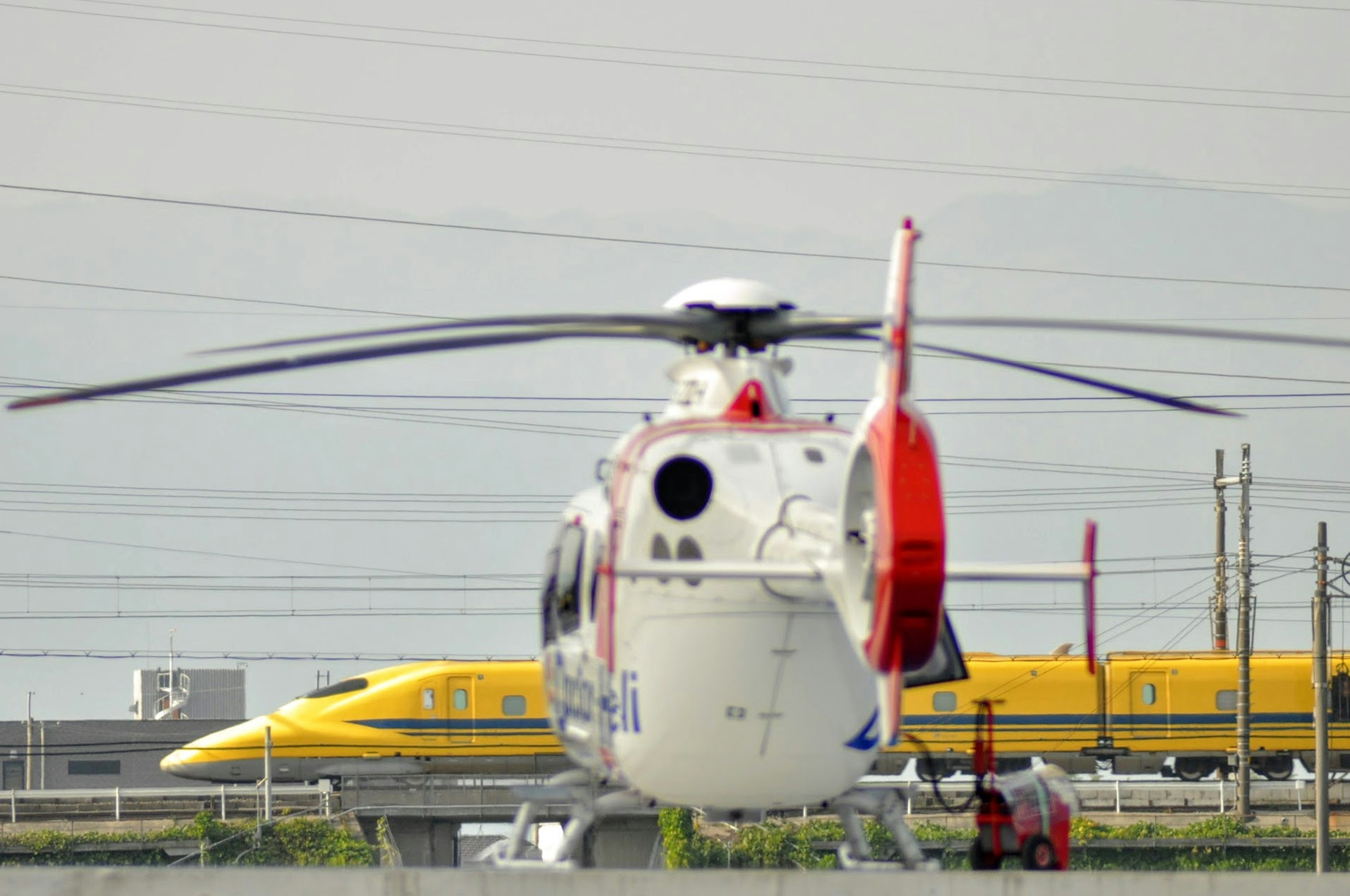 เฮลิคอปเตอร์กับรถไฟชิงกันเซนในพื้นหลัง