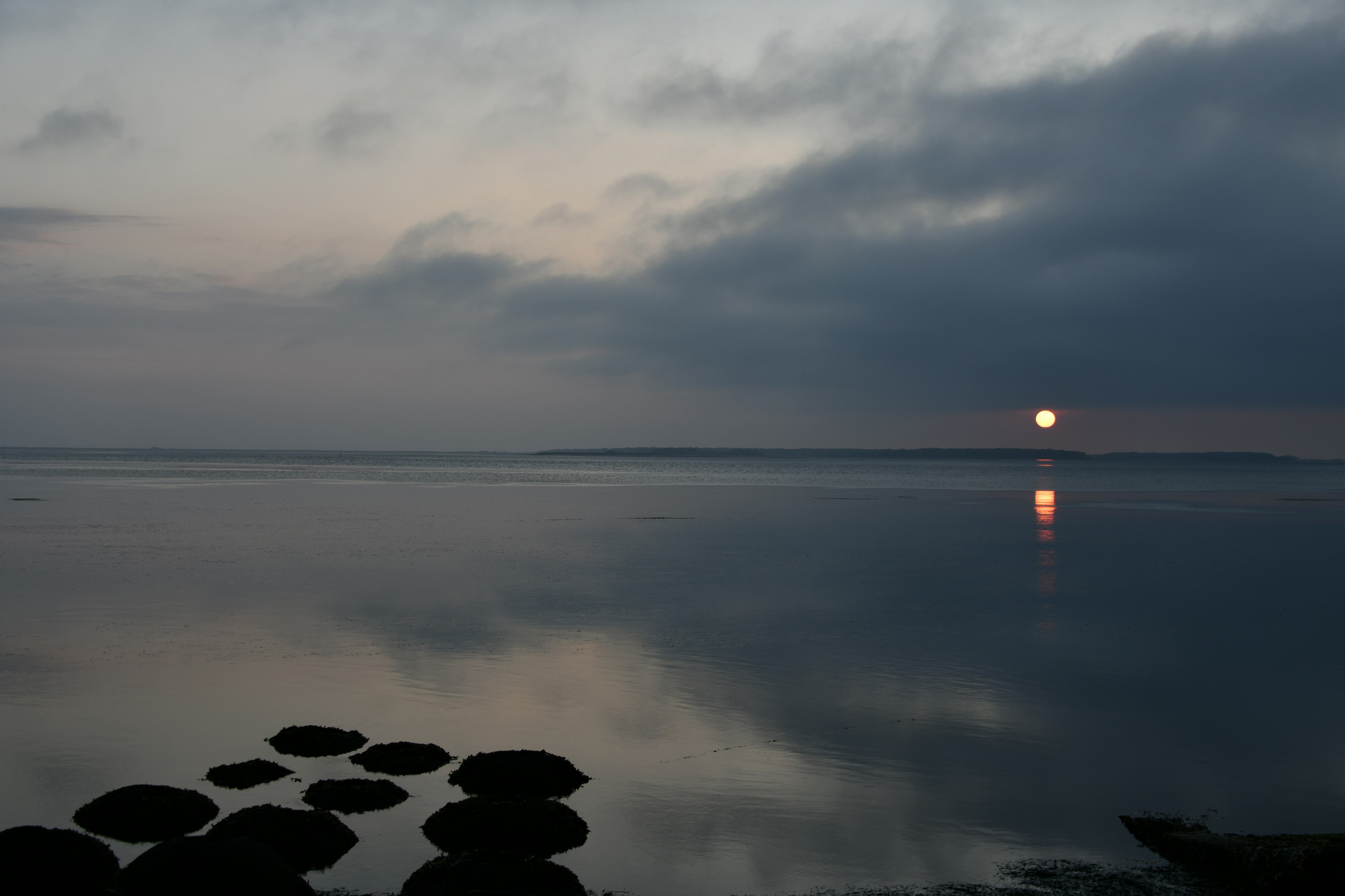 Eau calme reflétant la lumière du soir et des rochers