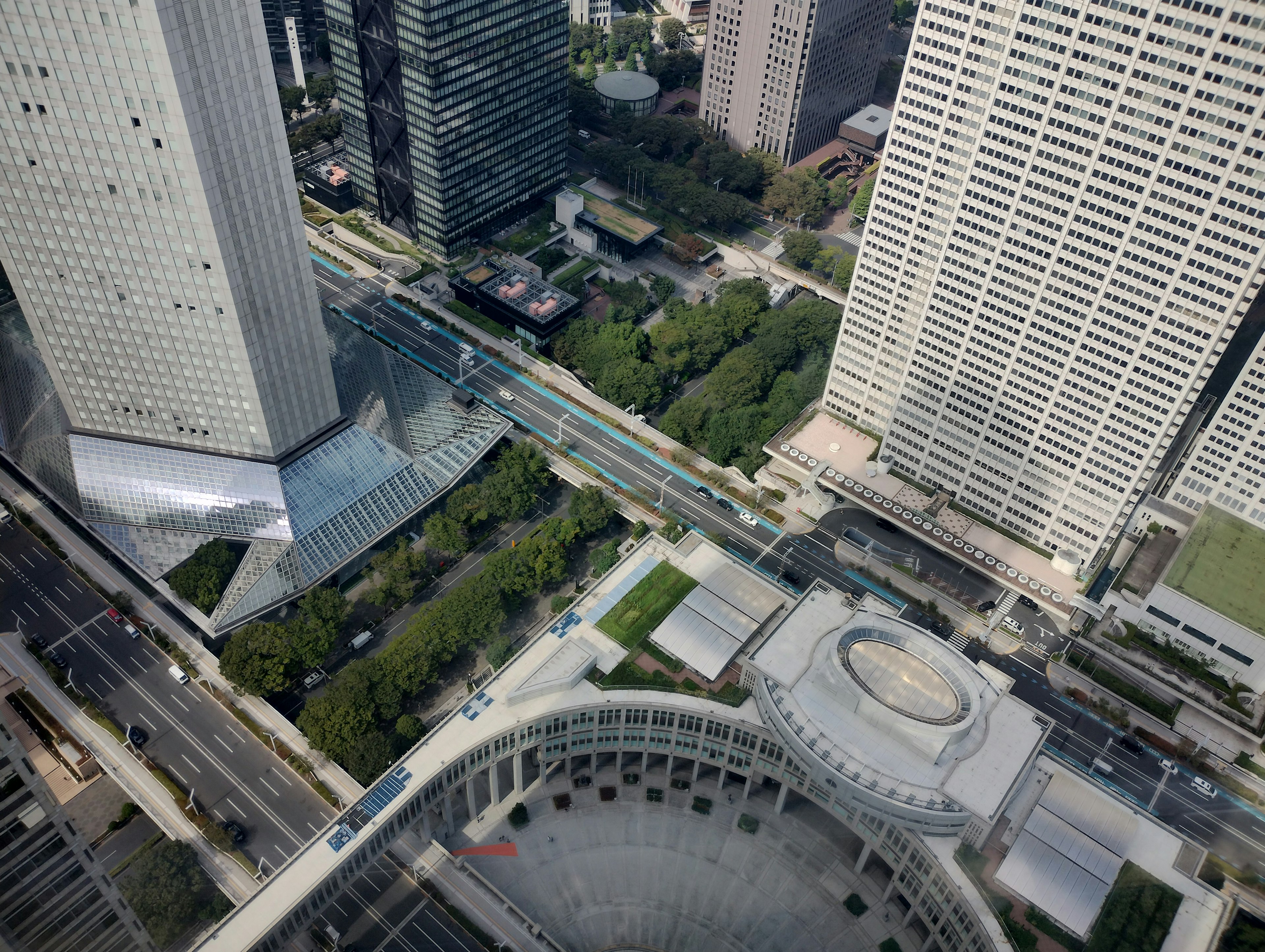 高層ビルの上から見た都市の景観 緑の公園と交通の交差点が見える